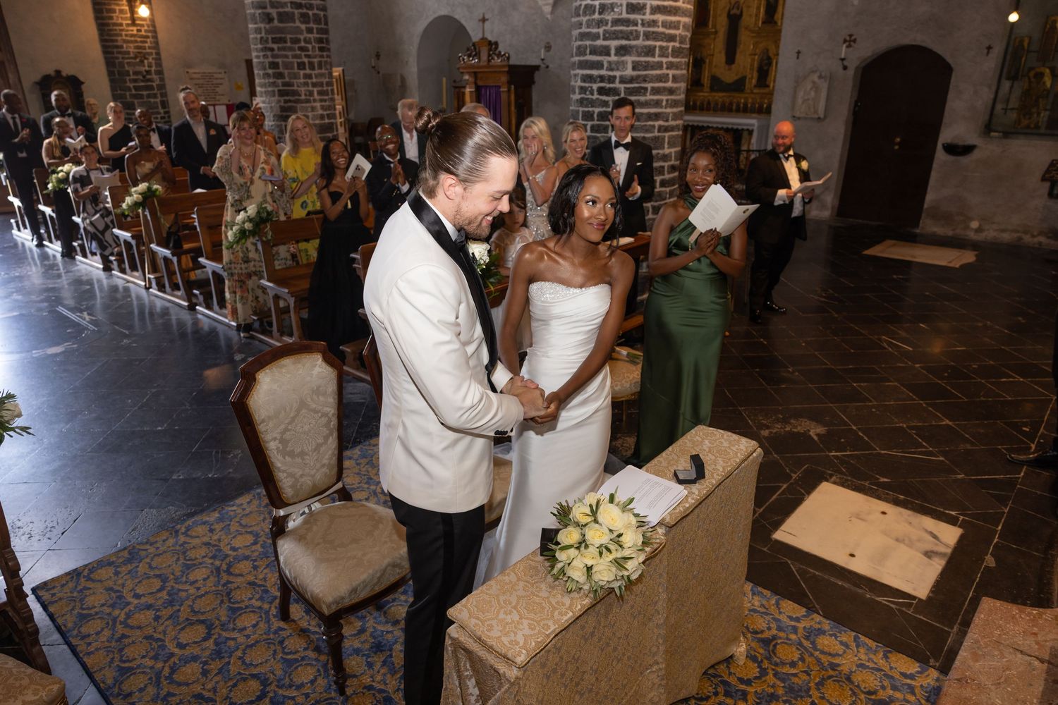 Wedding guests dance and celebrate on an elegant brick-walled dance floor during an evening reception.