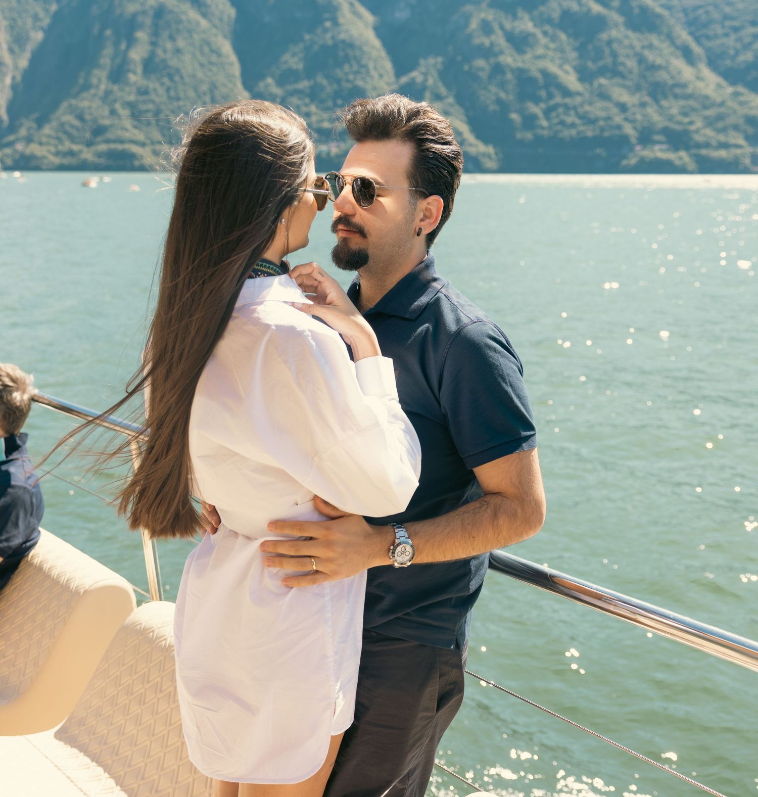 Couple sharing romantic moments on a boat deck with lake and mountain views.