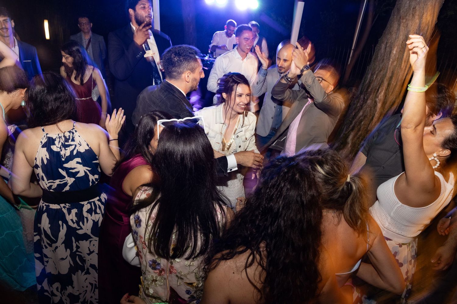 Wedding reception dance party with blue lighting and energetic crowd.