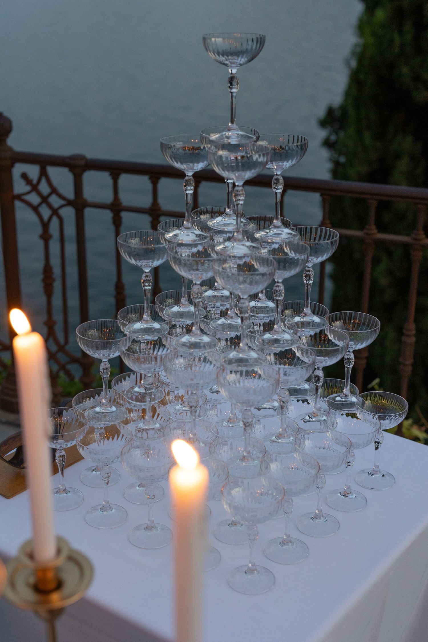 Champagne tower setup with white candles on a table at an elegant evening event.