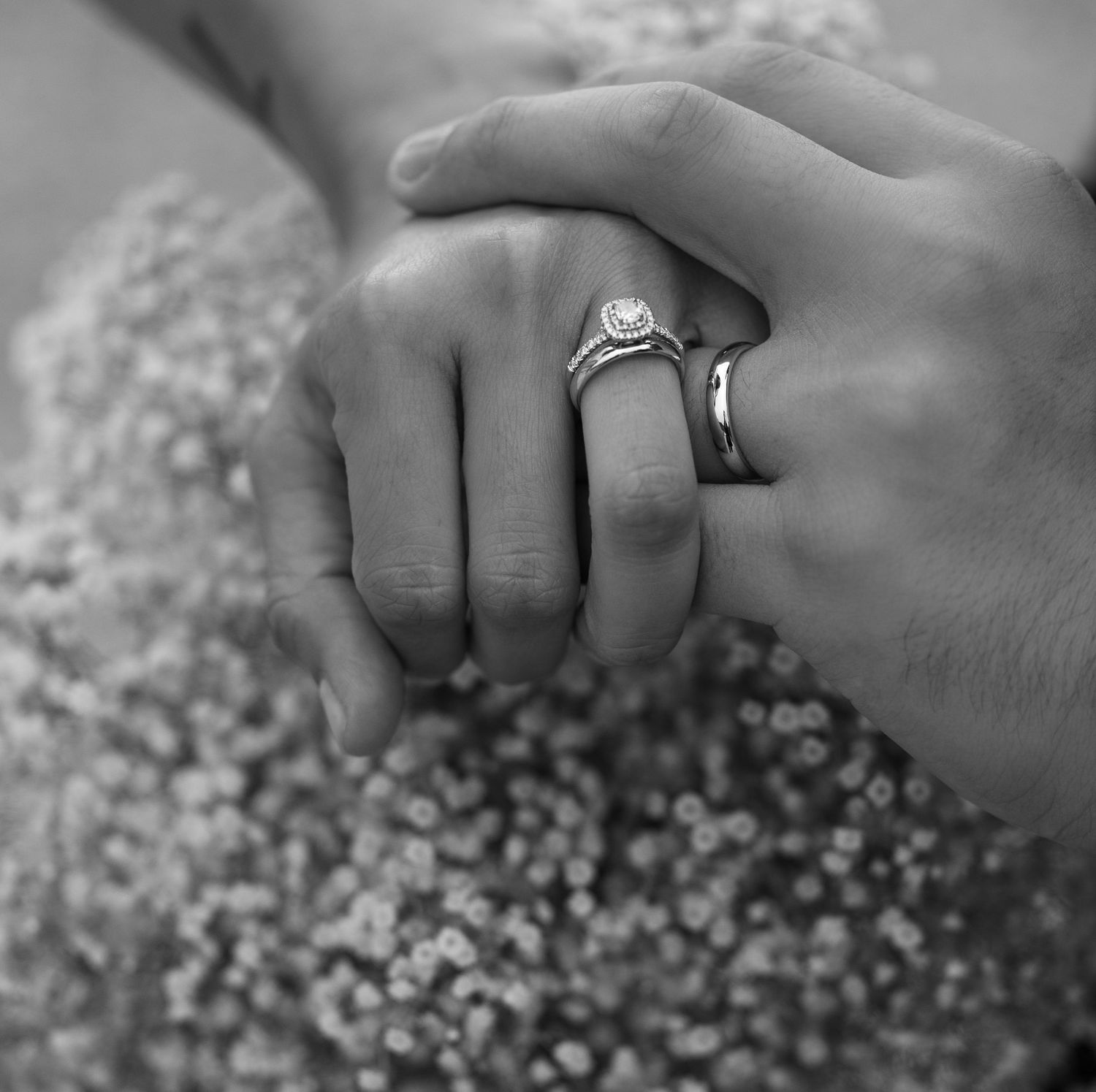 Close-up black and white photo of newlywed hands with wedding rings.