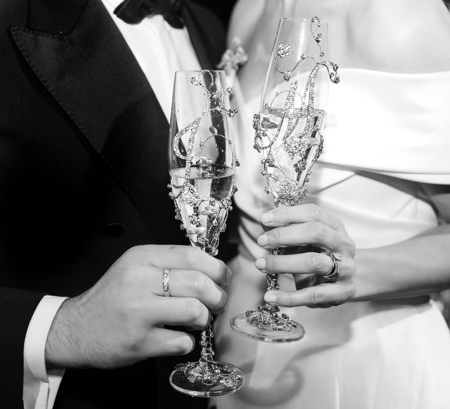 Black and white photo of champagne glasses clinking in celebration.