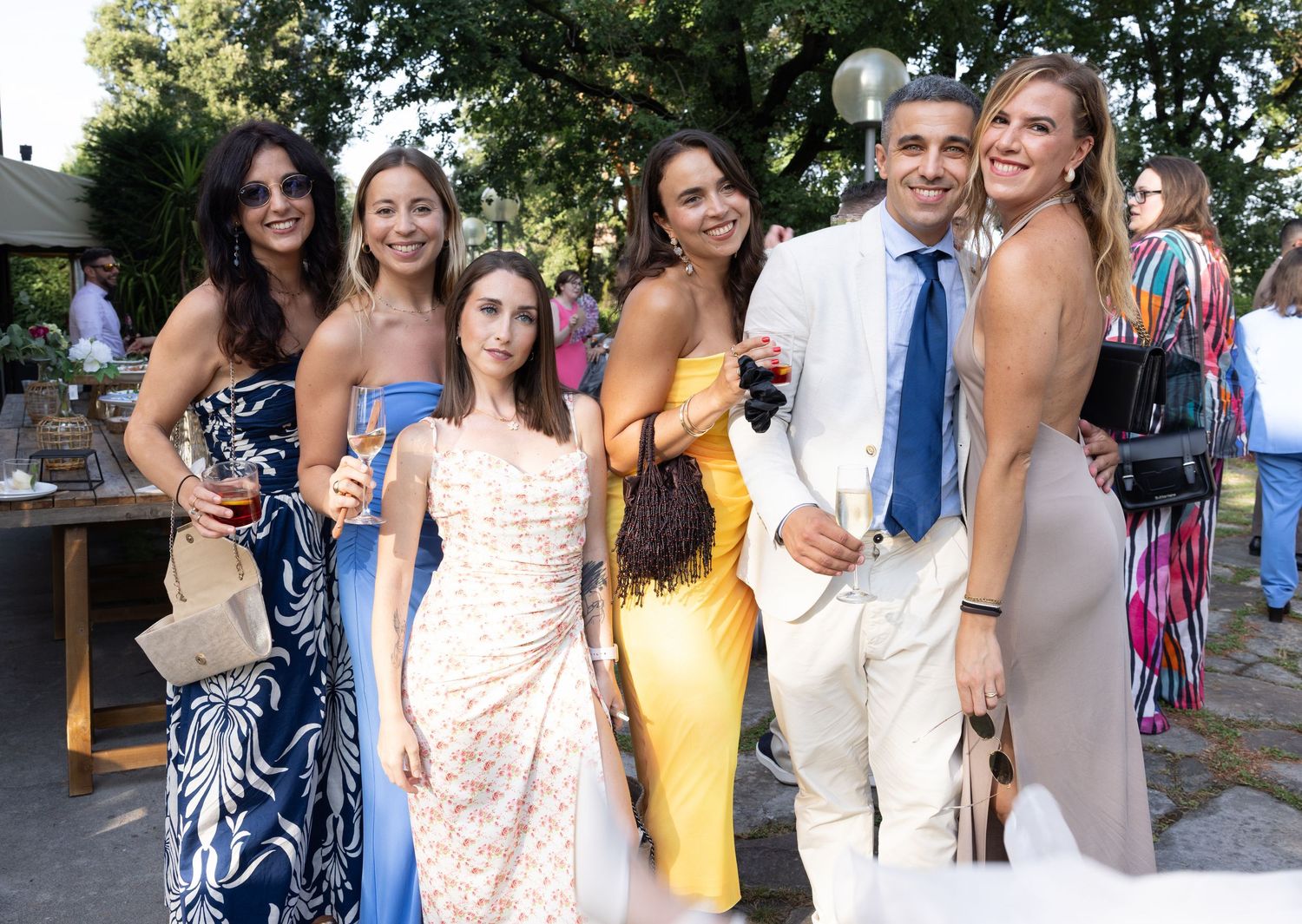 Wedding party poses outdoors in elegant dresses and formal attire.