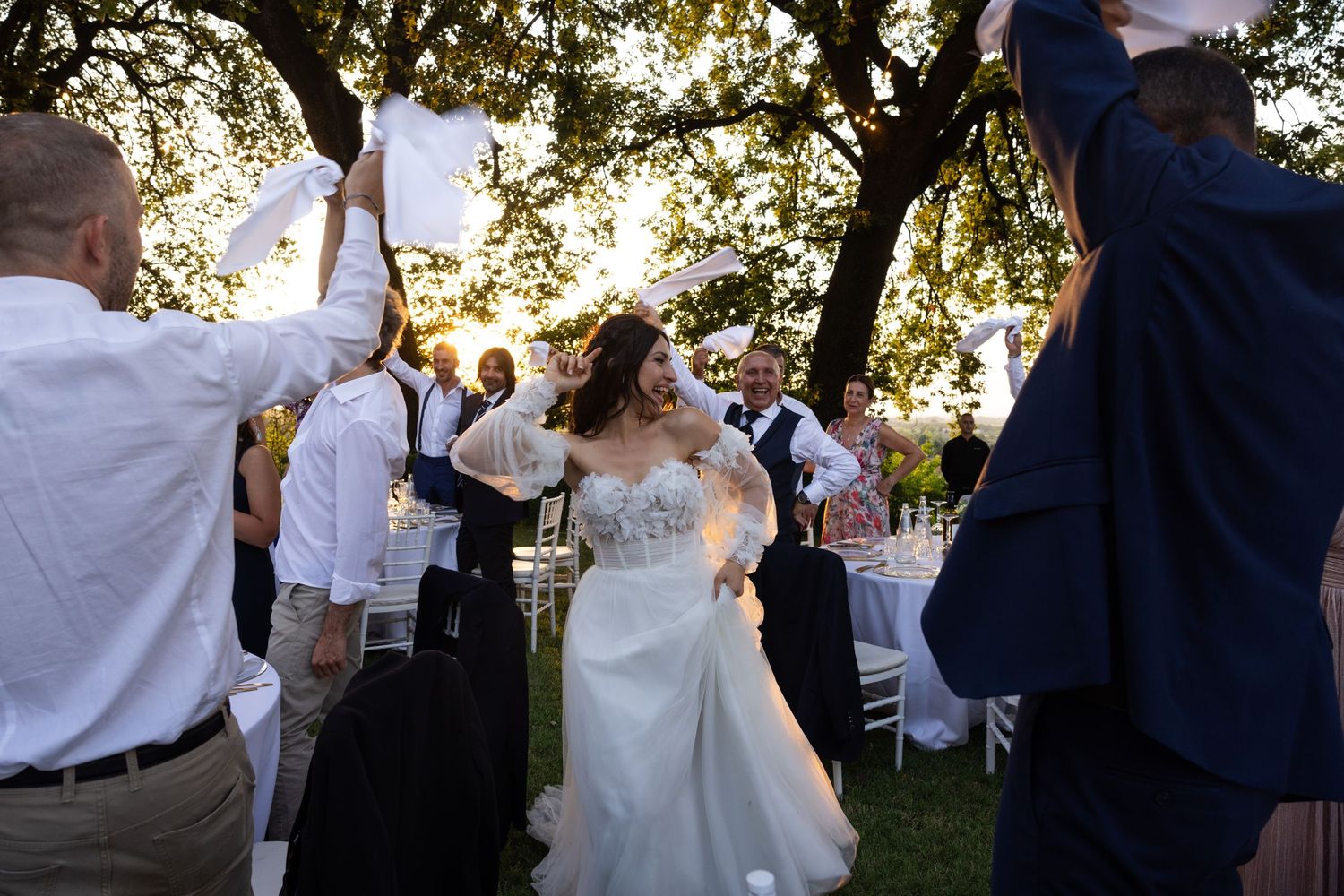 Wedding celebration with guests dancing outdoors at sunset.