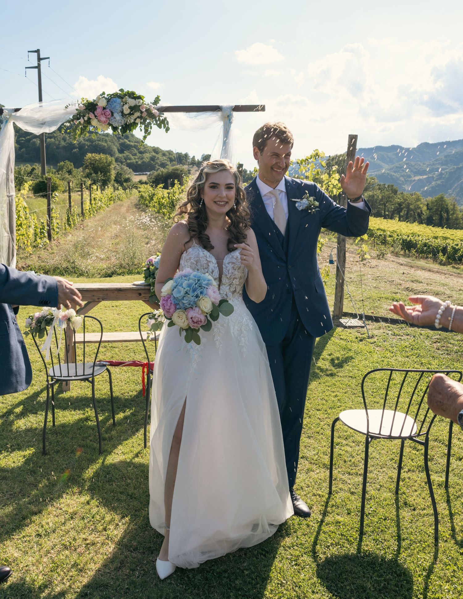 A couple celebrates after their wedding ceremony in front of a rustic mountain backdrop.