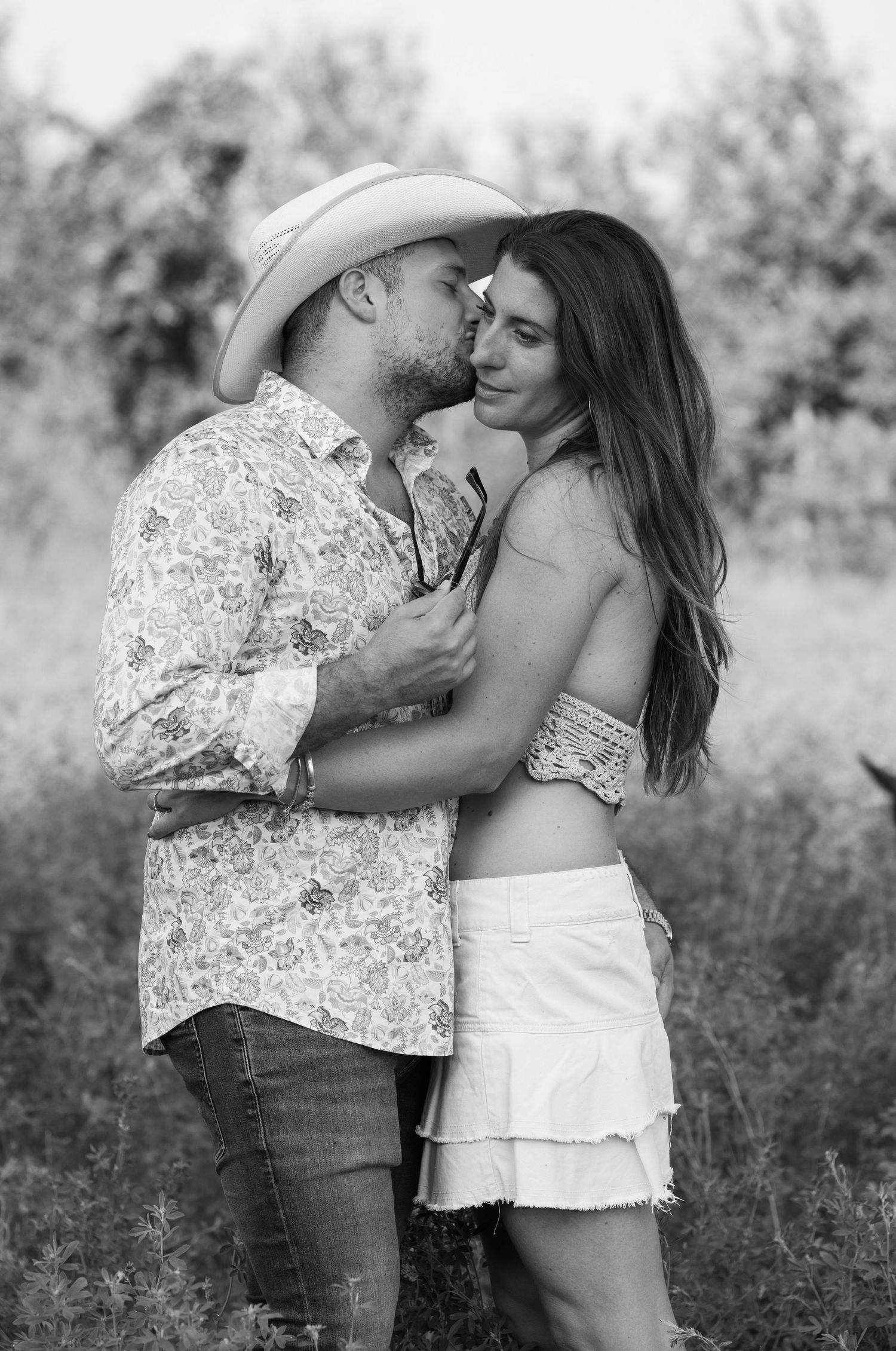 Intimate black and white photos of couple sharing tender moments in a field.