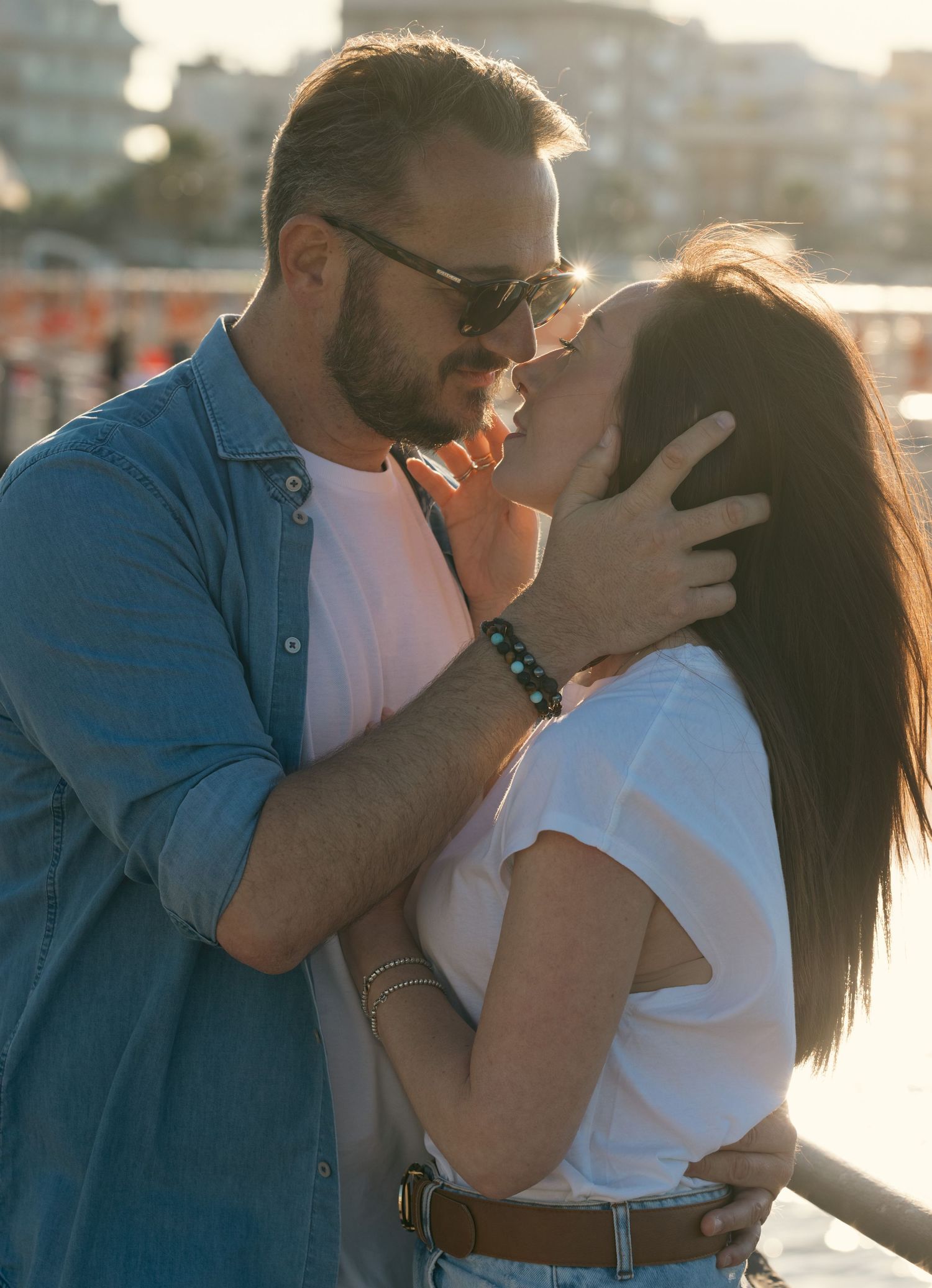 Sunset portrait of couple sharing an intimate moment against urban backdrop.