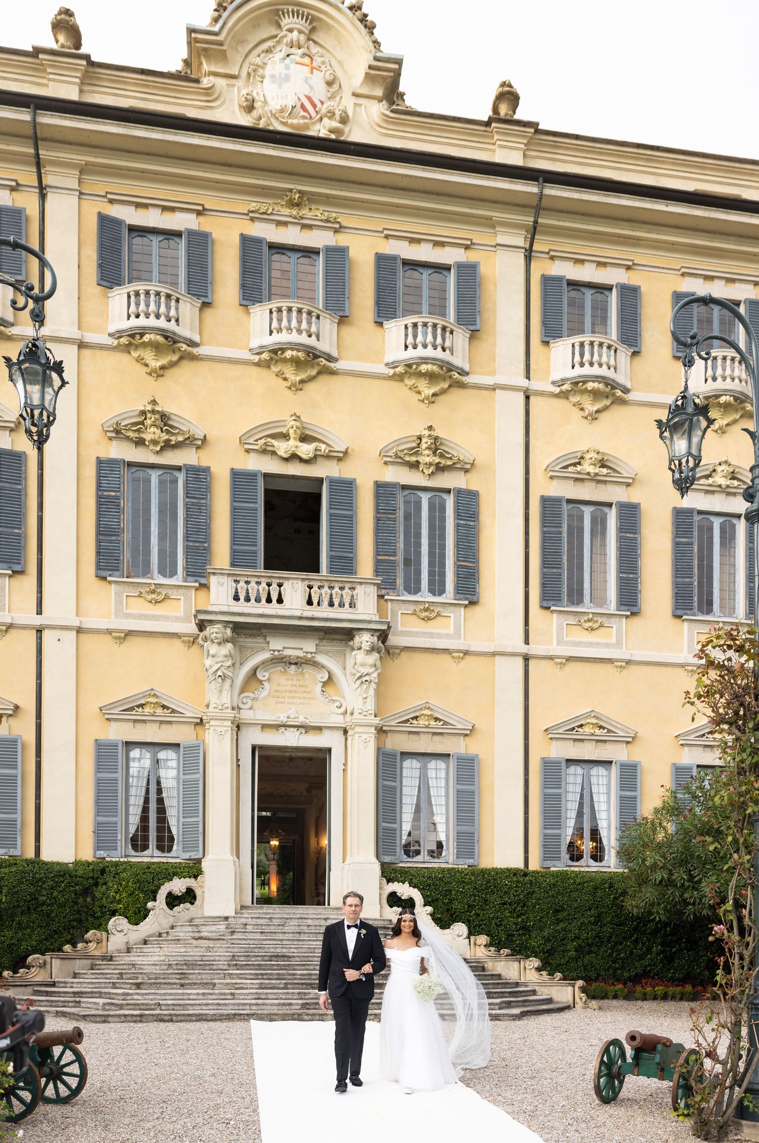 Exterior of grand yellow Italian villa with ornate architectural details and stone steps.