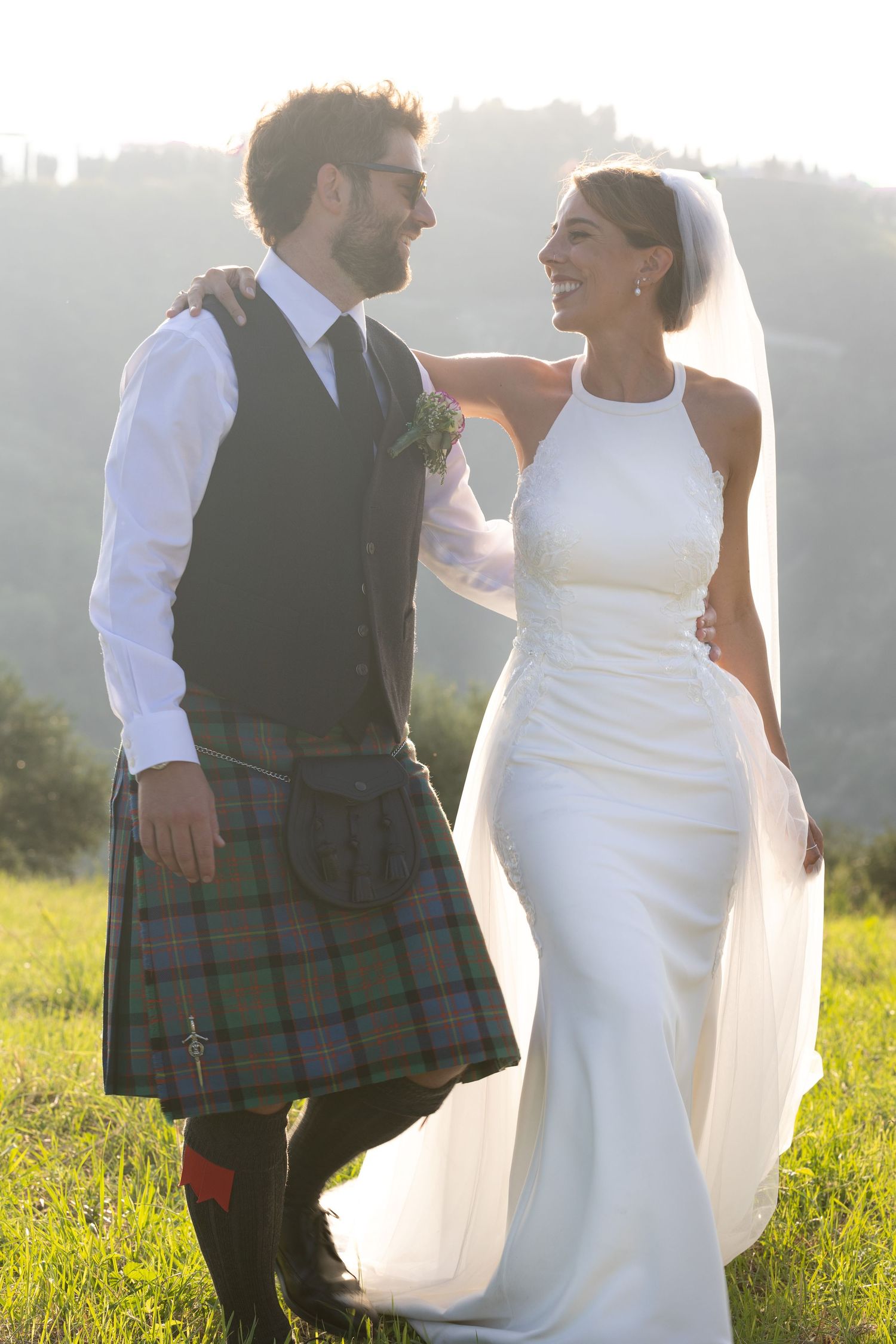 A romantic wedding couple poses outdoors, with the groom wearing a traditional Scottish kilt.