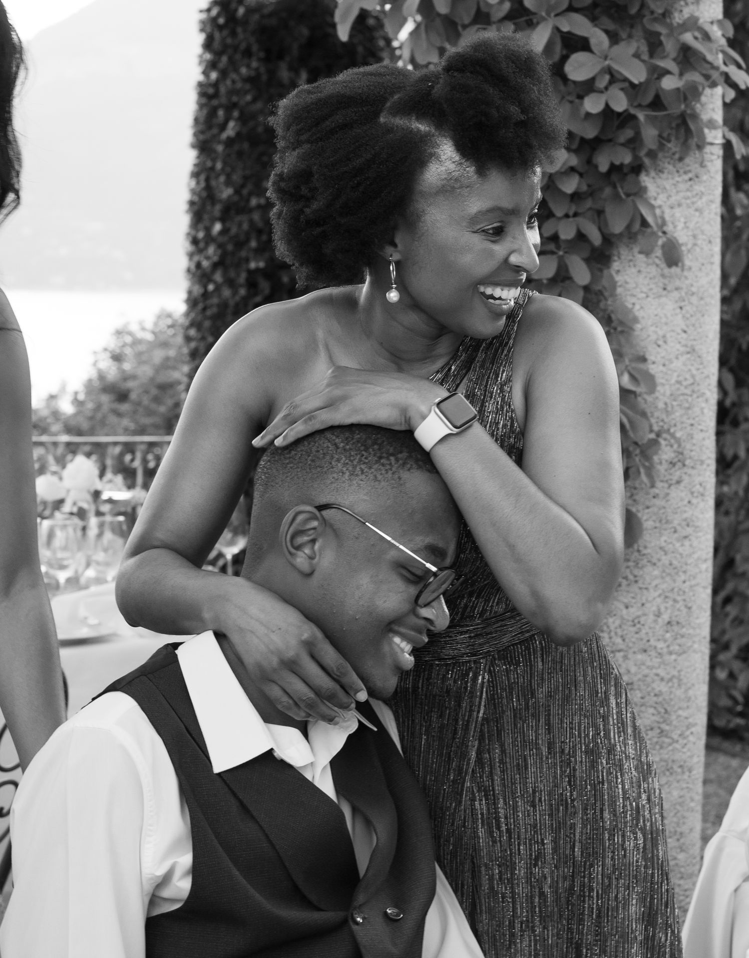 A black and white photograph showing joyful expressions and intimate moments between people in a candid setting.