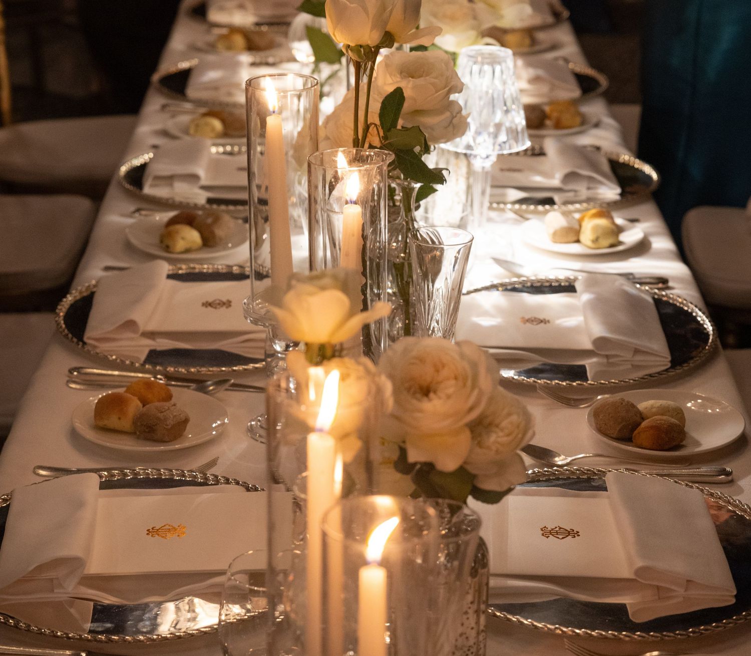 Candlelit wedding reception table with formal place settings and floral arrangements.