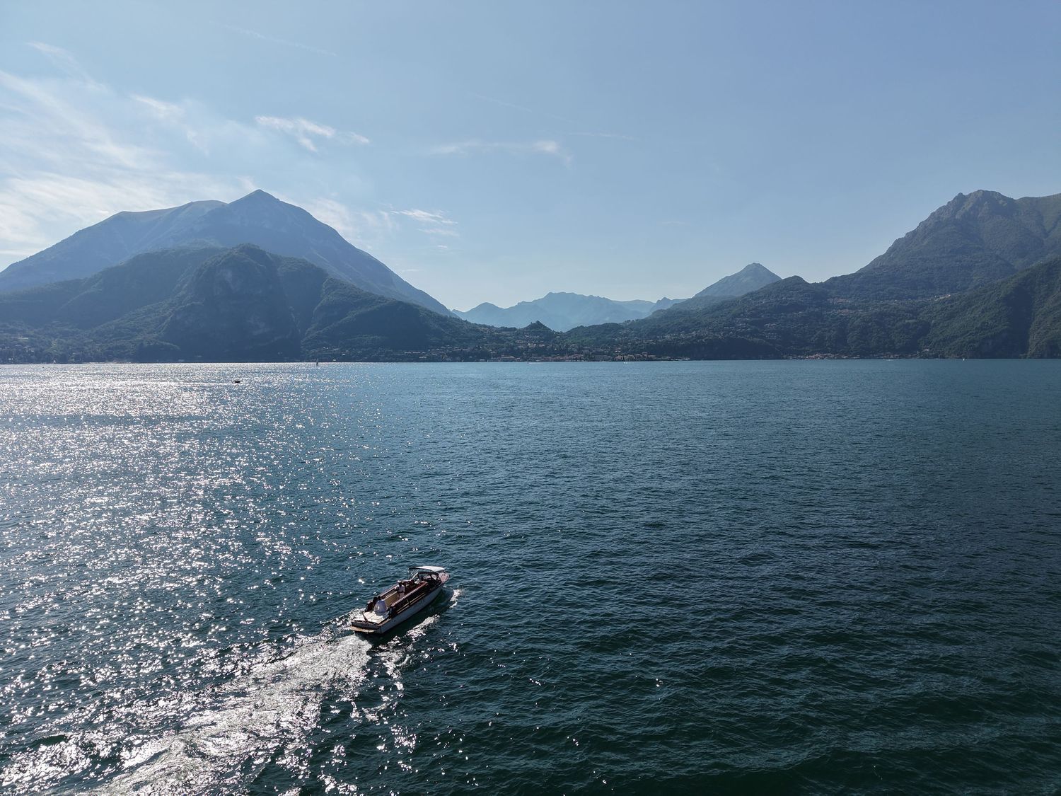 Scenic mountain lake view with sparkling water and snow-capped peaks in the background.