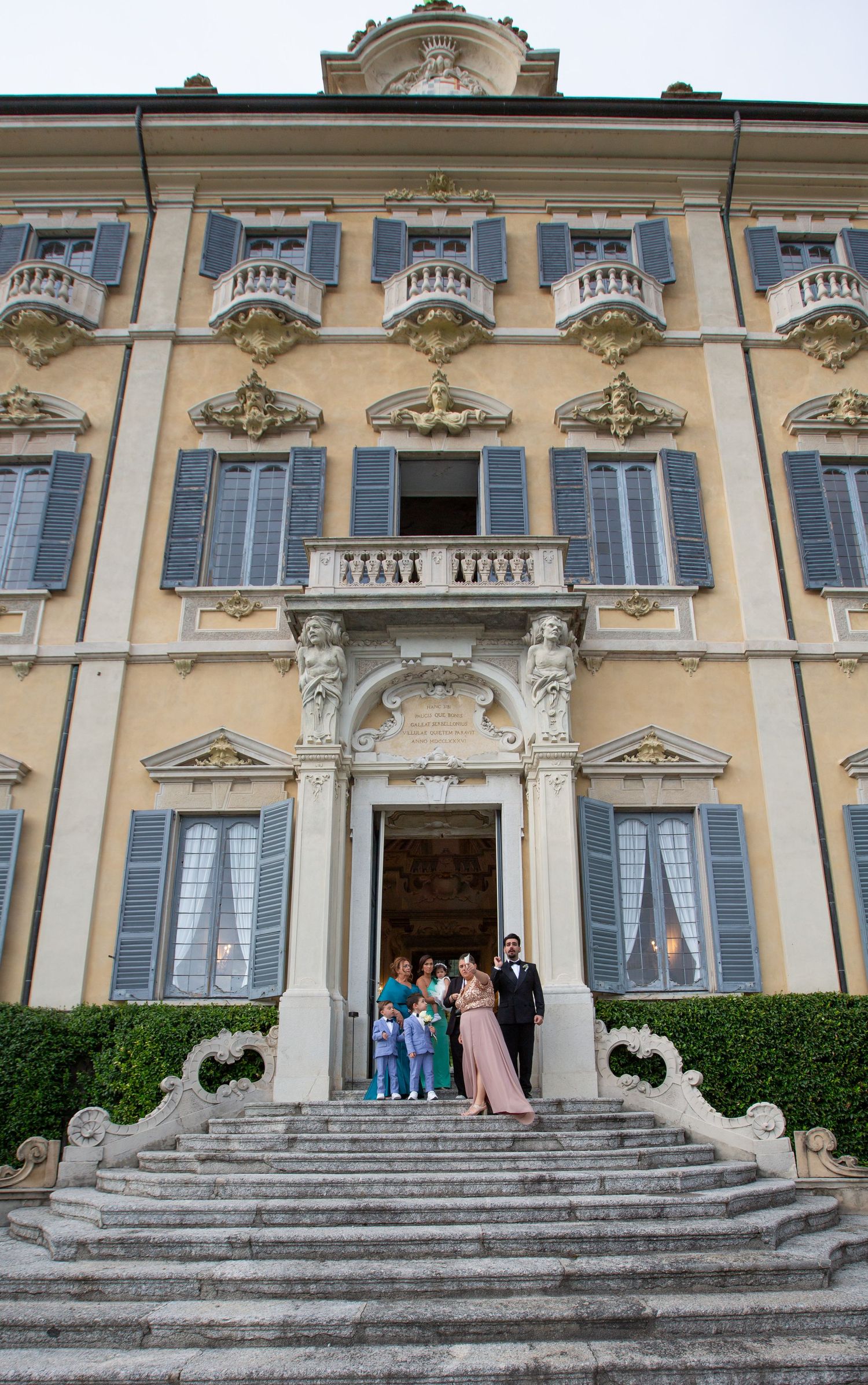 Grand Italian villa with ornate architecture and stone steps leading to entrance doors.