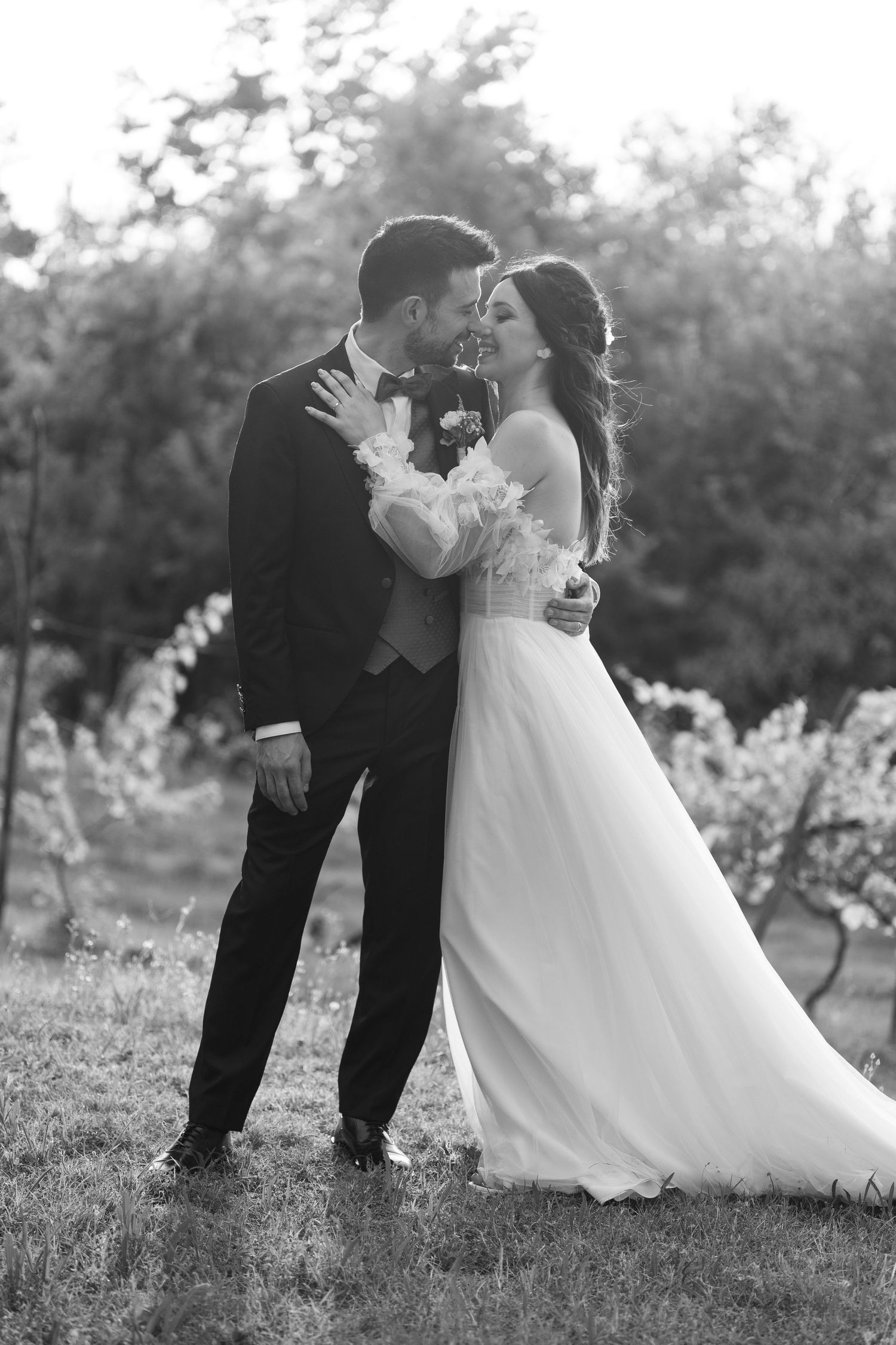 A black and white portrait of a wedding couple sharing an intimate moment in a garden setting.