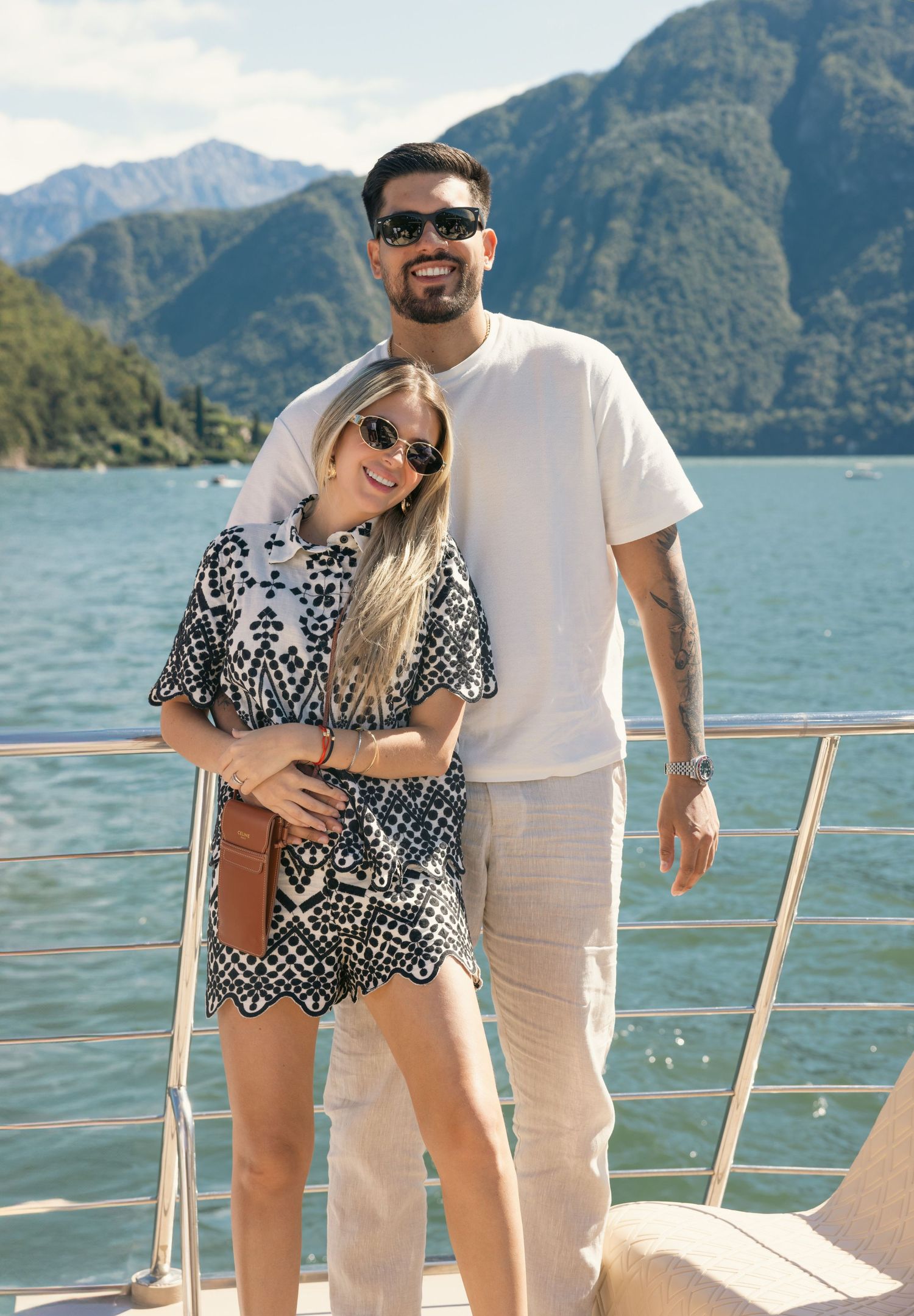 Friends enjoying a sunny day on a yacht deck with mountain views.