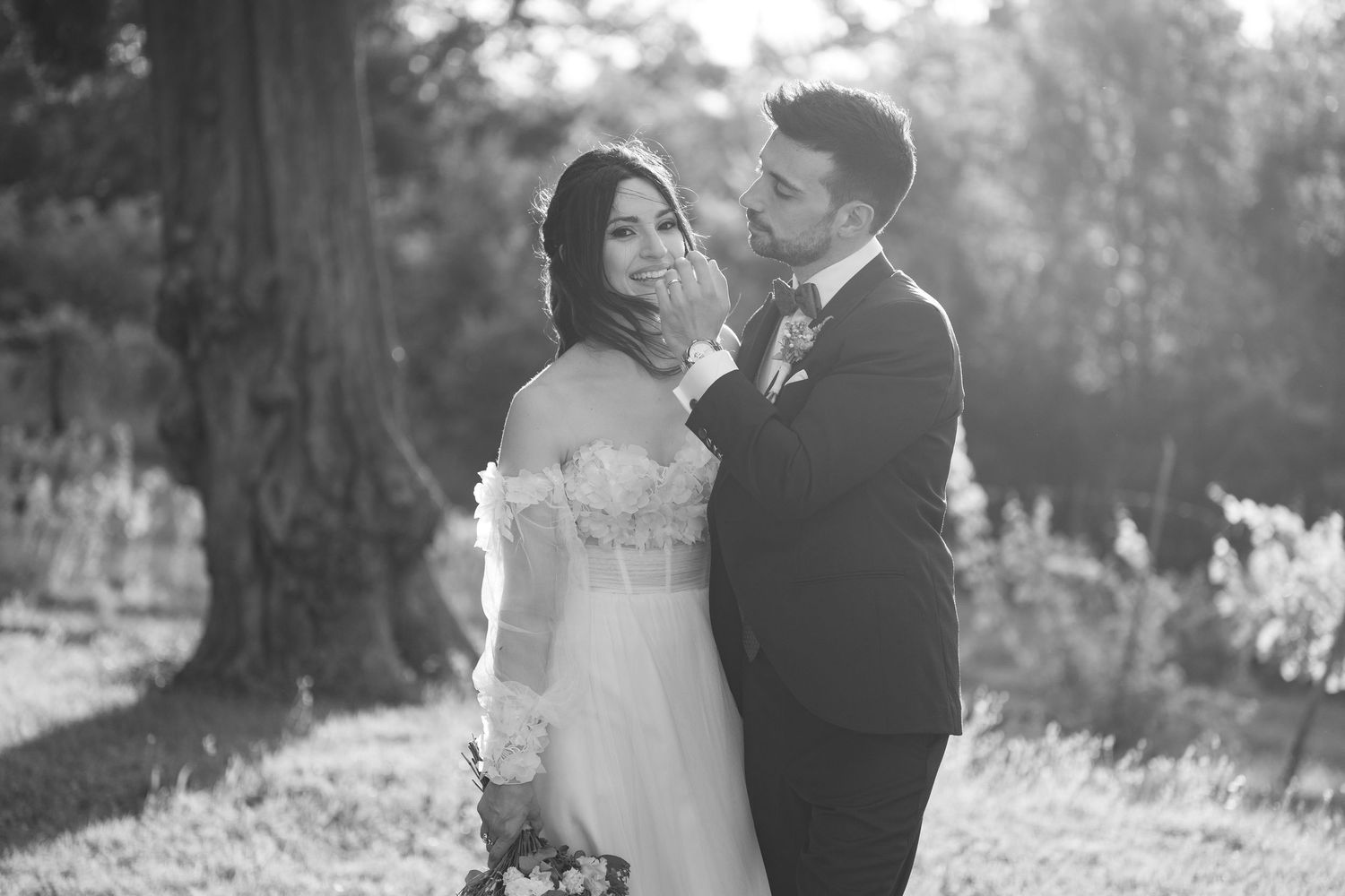 Black and white portrait of a couple sharing a tender moment in their wedding attire.