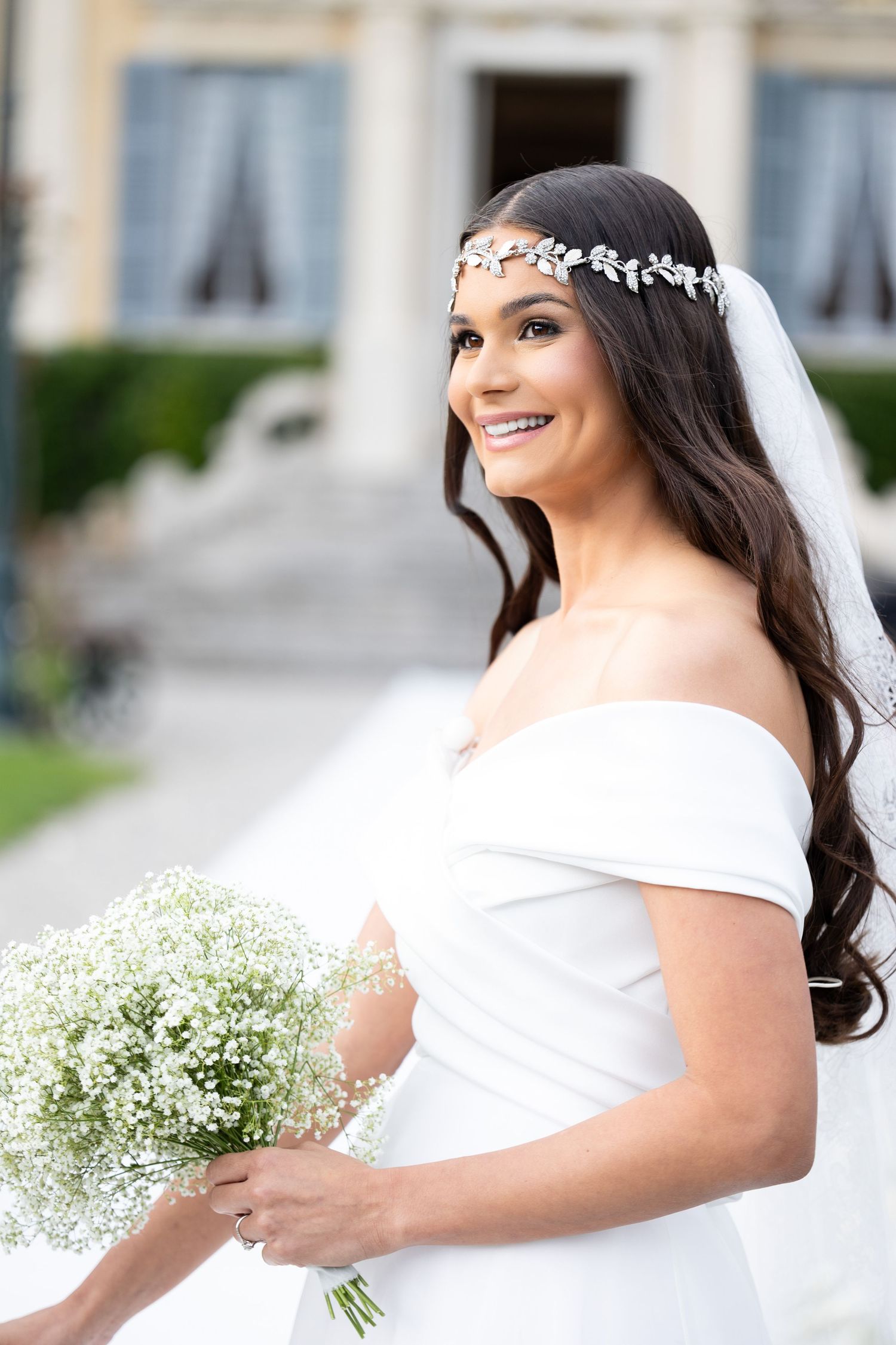 Elegant bridal portrait featuring a white off-shoulder wedding dress and baby's breath bouquet.