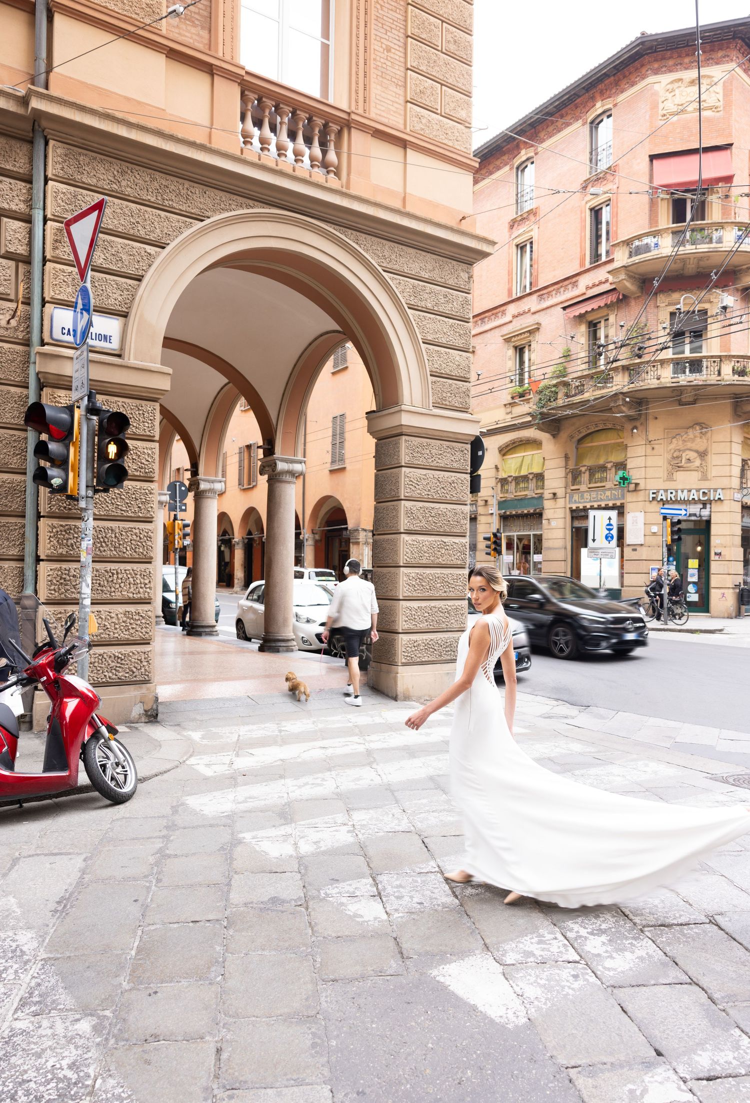 Wedding dress flowing dramatically under Italian stone archways in an historic city street.