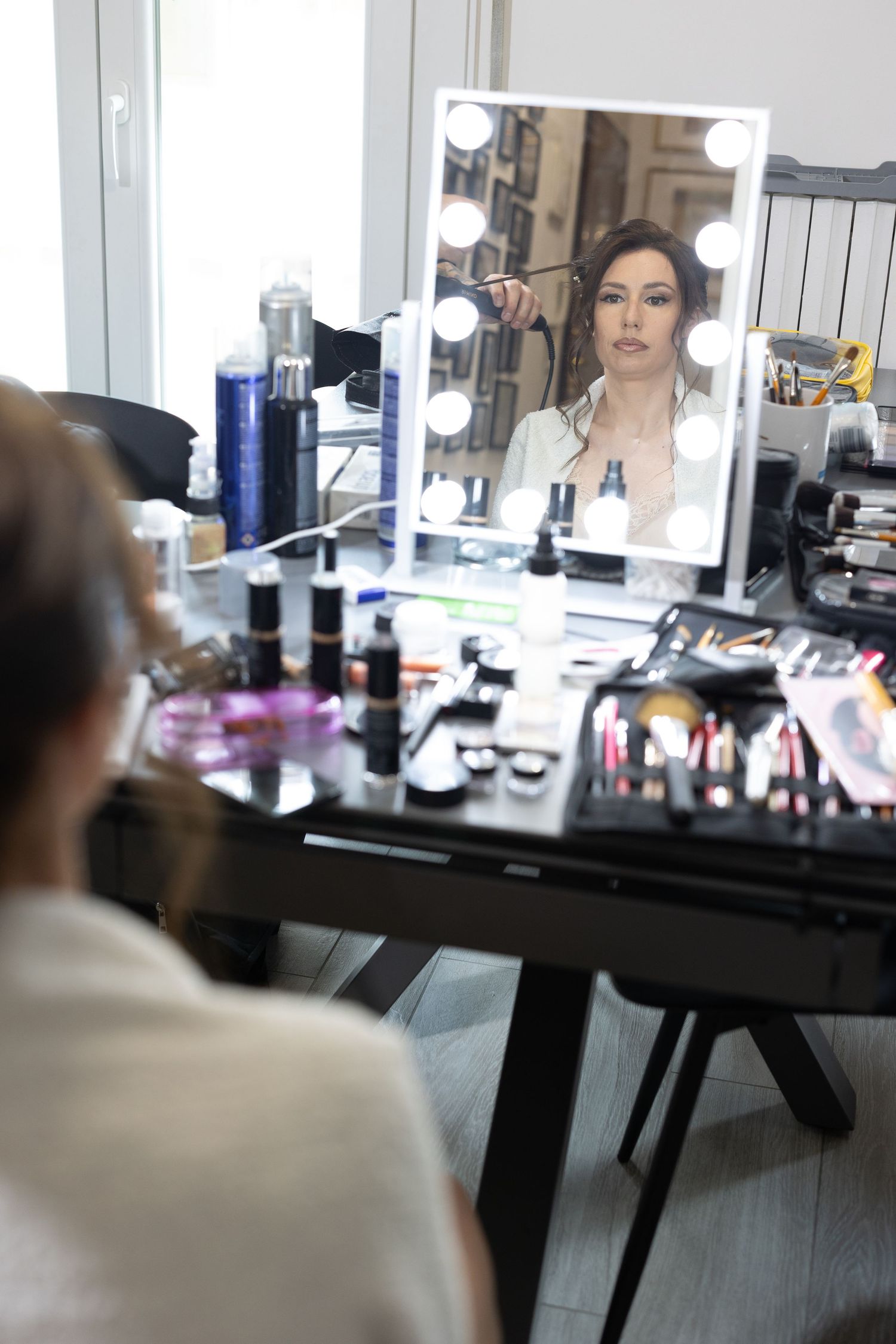 Professional makeup station with illuminated mirrors and beauty products.