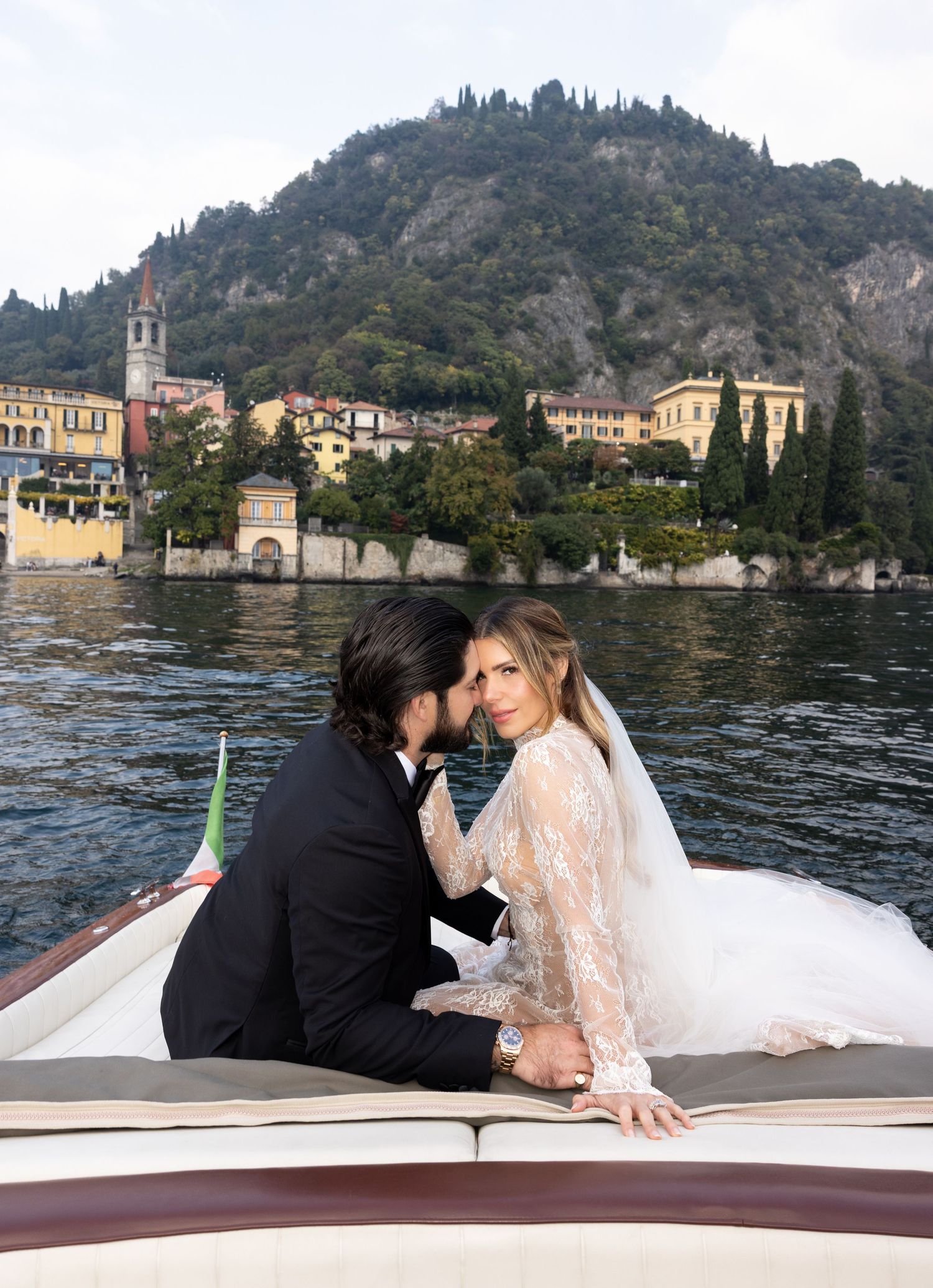 Romantic moments captured on a wooden boat with Italian lakeside villas and mountains in the background.