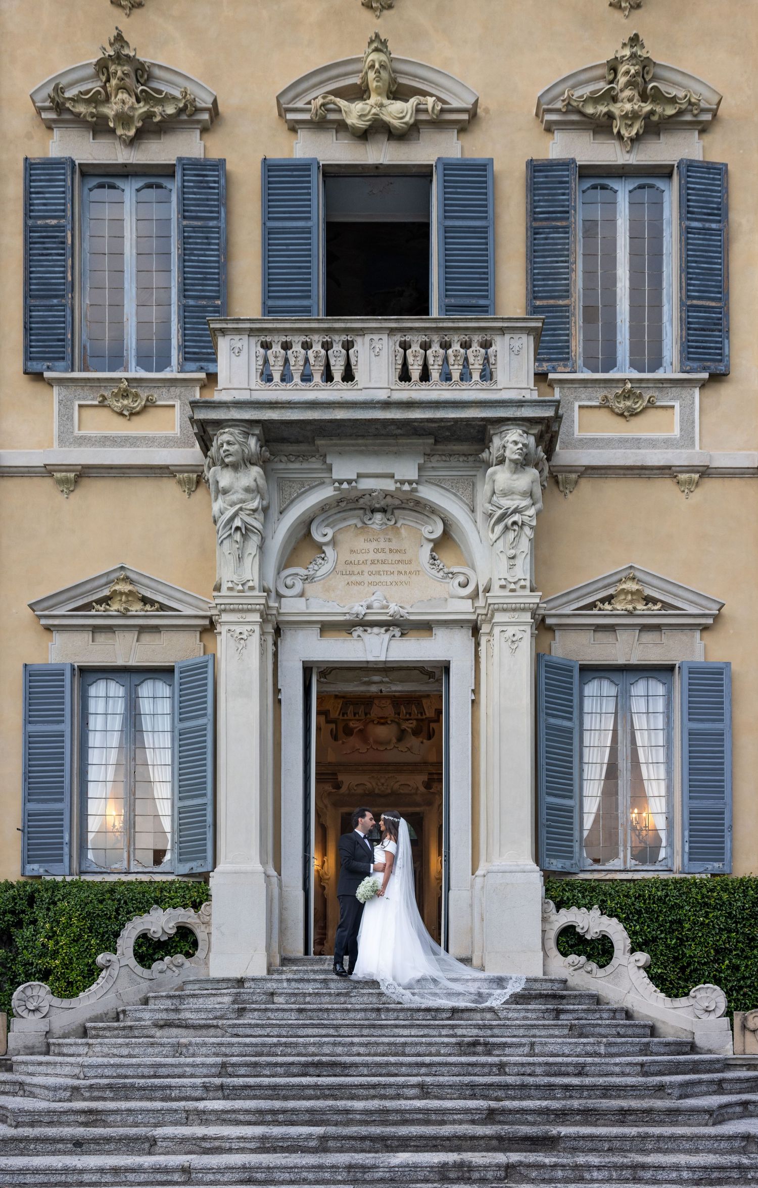 Elegant Italian villa with blue shutters and ornate architectural details serves as wedding venue backdrop.