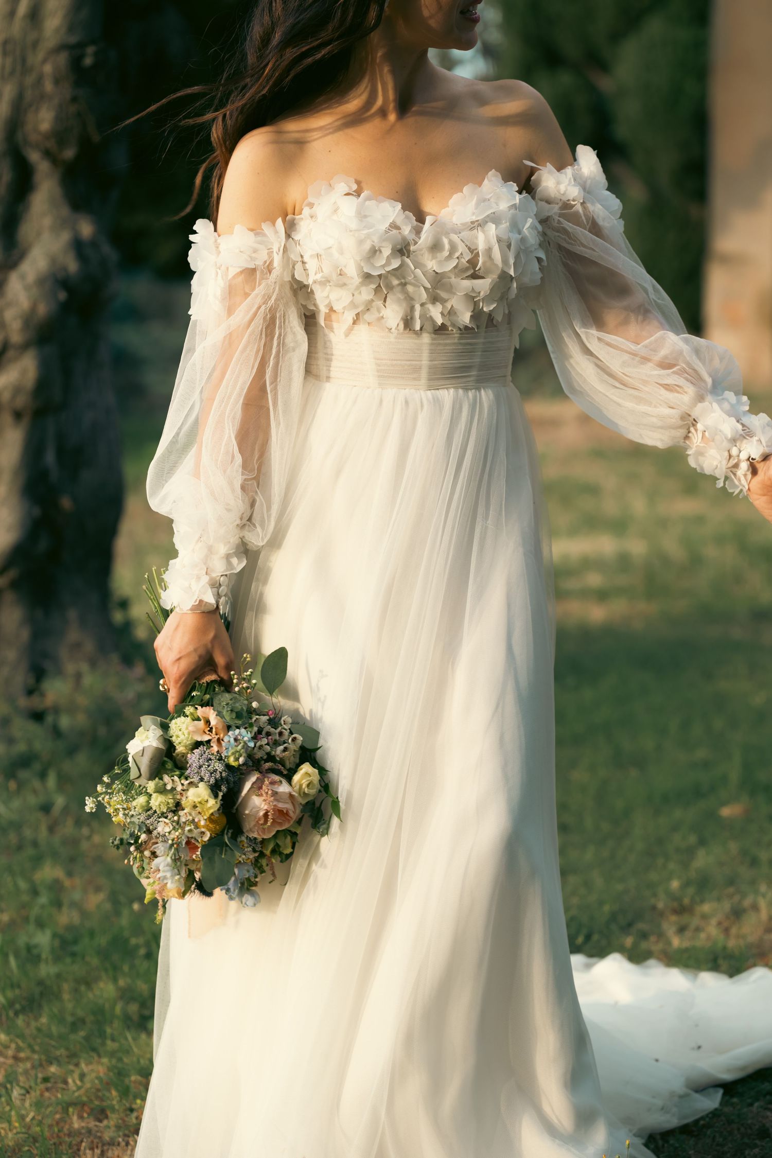 Ethereal wedding dress details with floral accents and flowing fabric in natural light.
