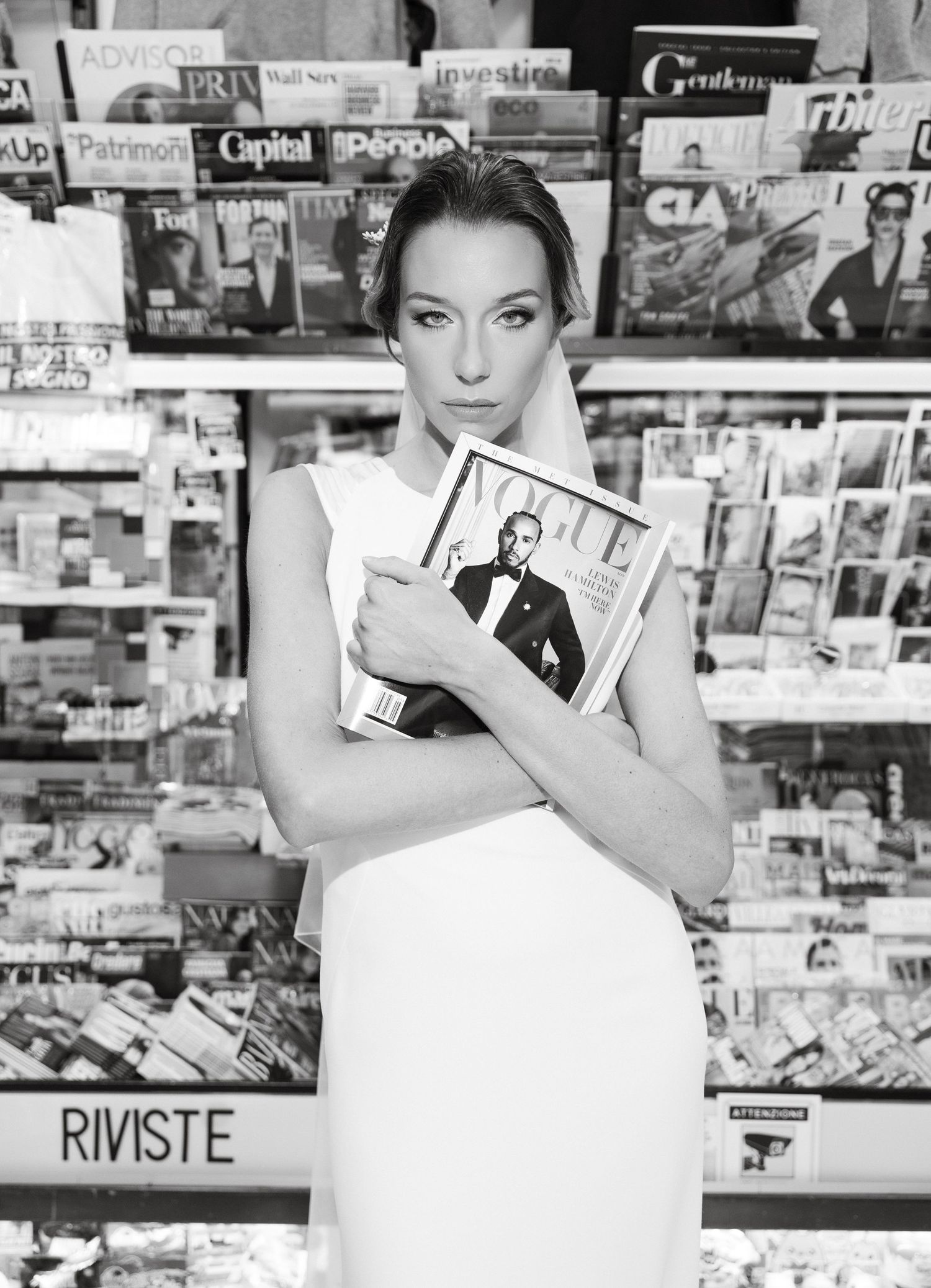 Black and white photo of bridal shoot in a newsstand with magazine displays.