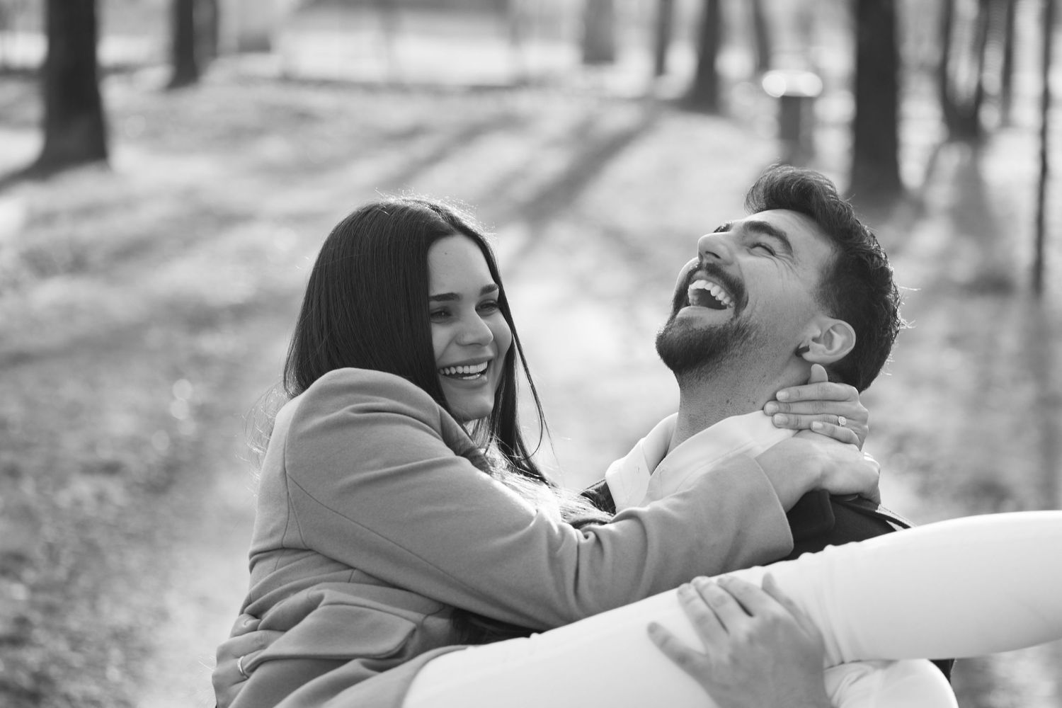 Couple sharing a joyful moment together on a tree-lined path.