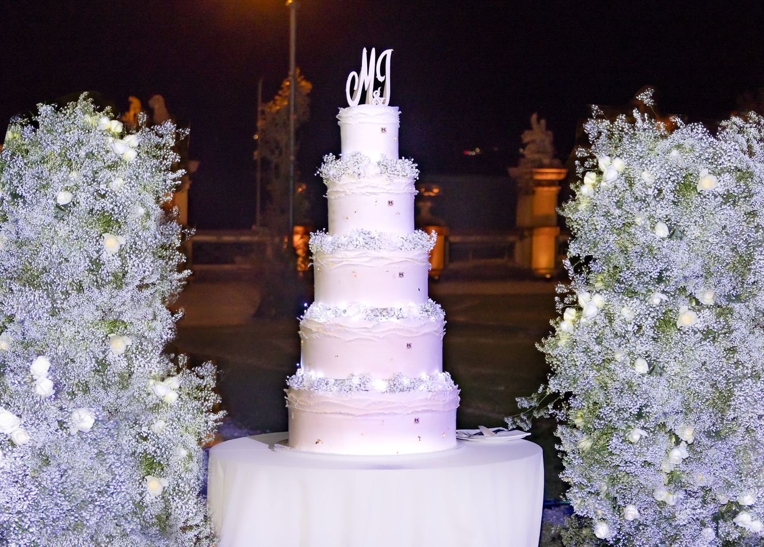 An elegant white wedding cake decorated with delicate flowers and crystal accents.