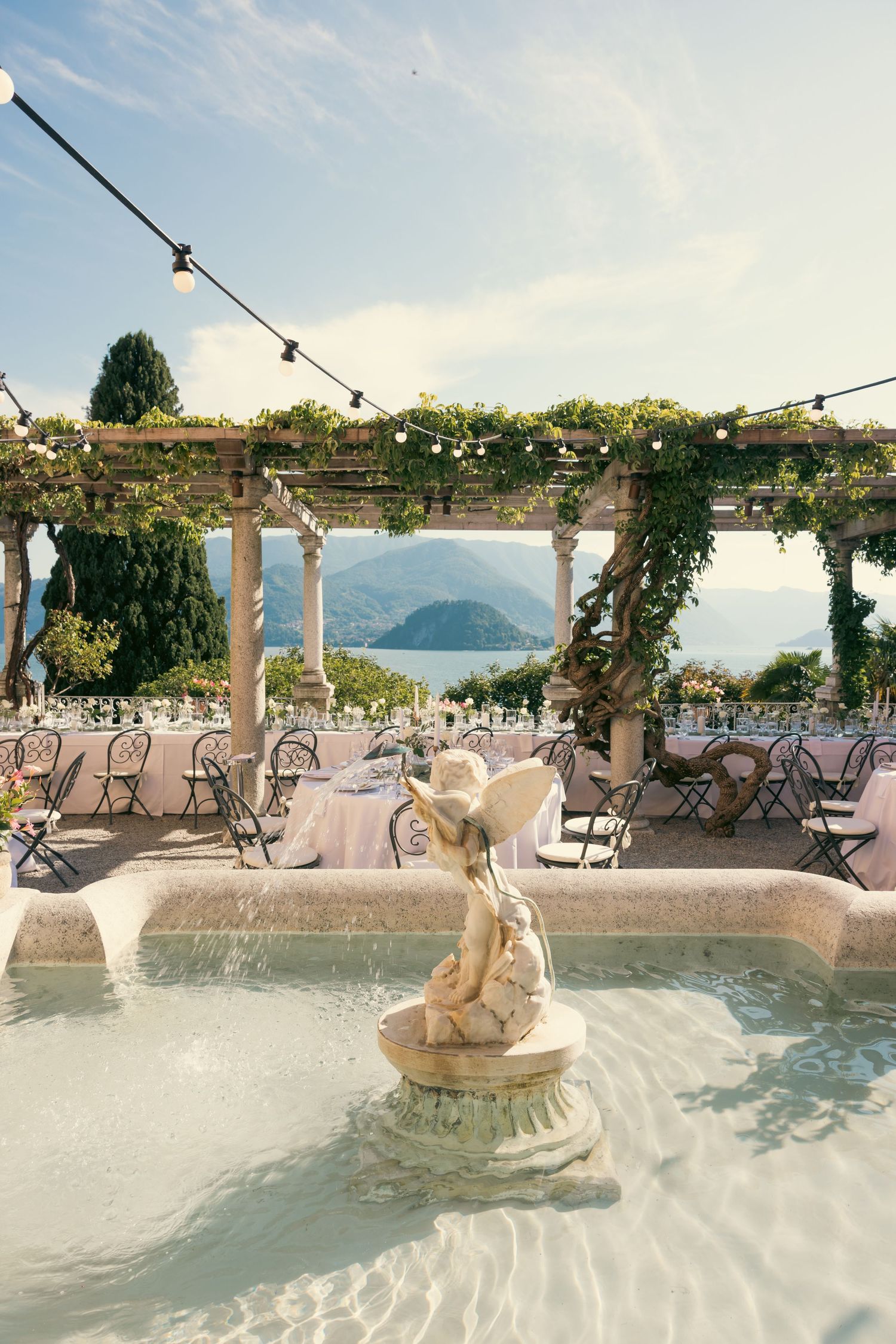 A luxurious outdoor wedding venue with white decor, string lights, and stunning lake views in the background.