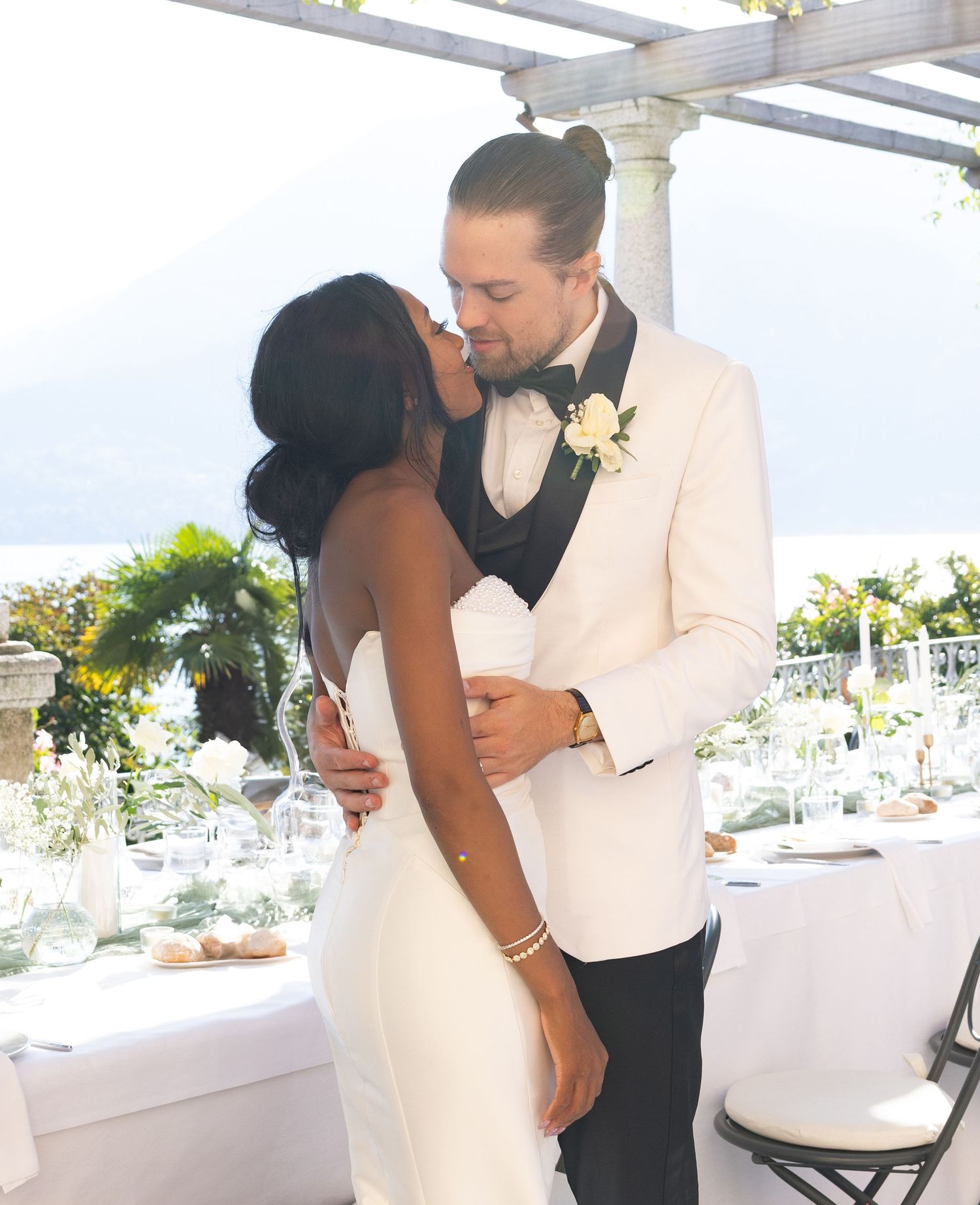 A couple in formal wedding attire shares an intimate moment at an elegantly decorated reception venue.