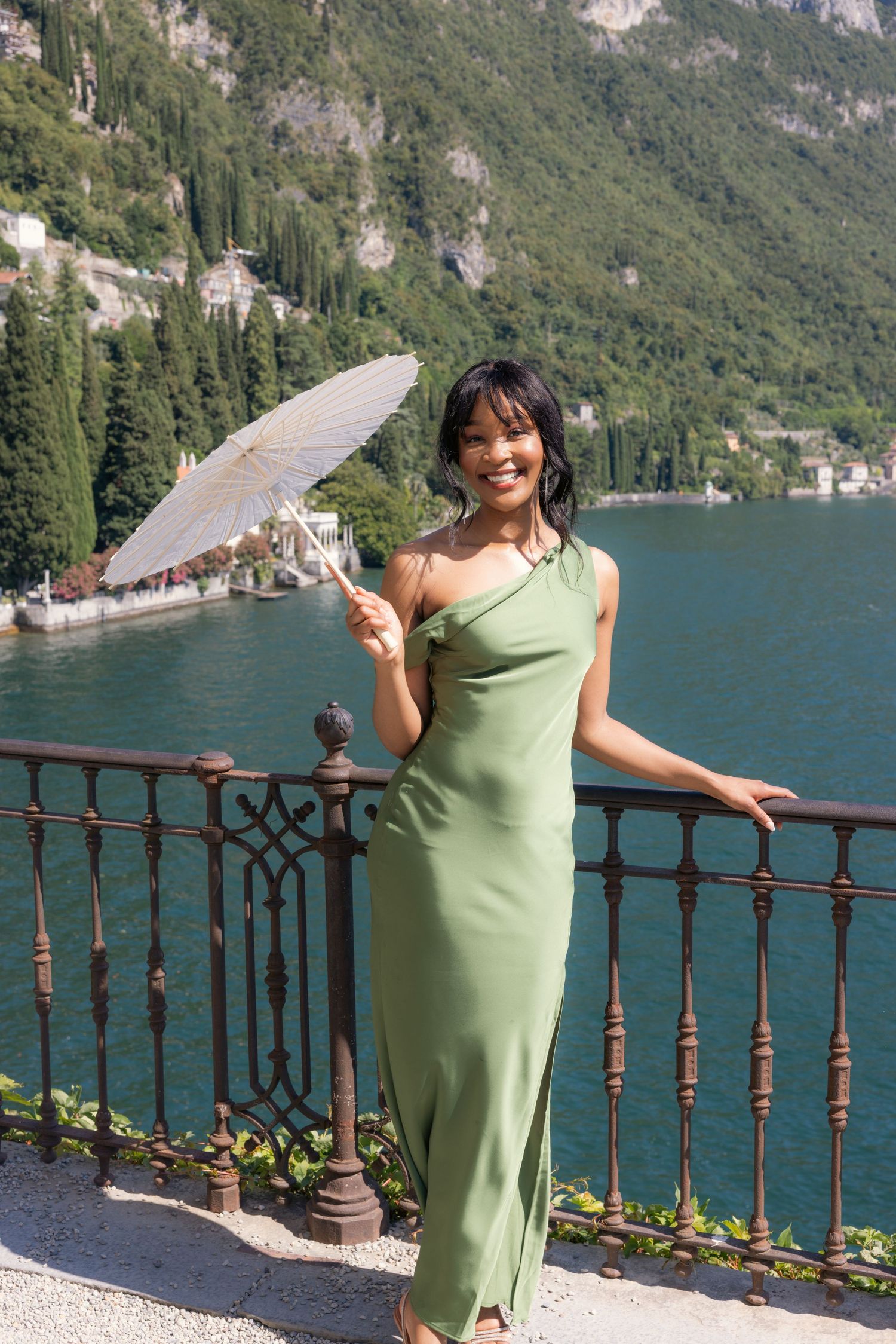 A scenic lakeside view in Italy with mountains and a decorative railing in the foreground.