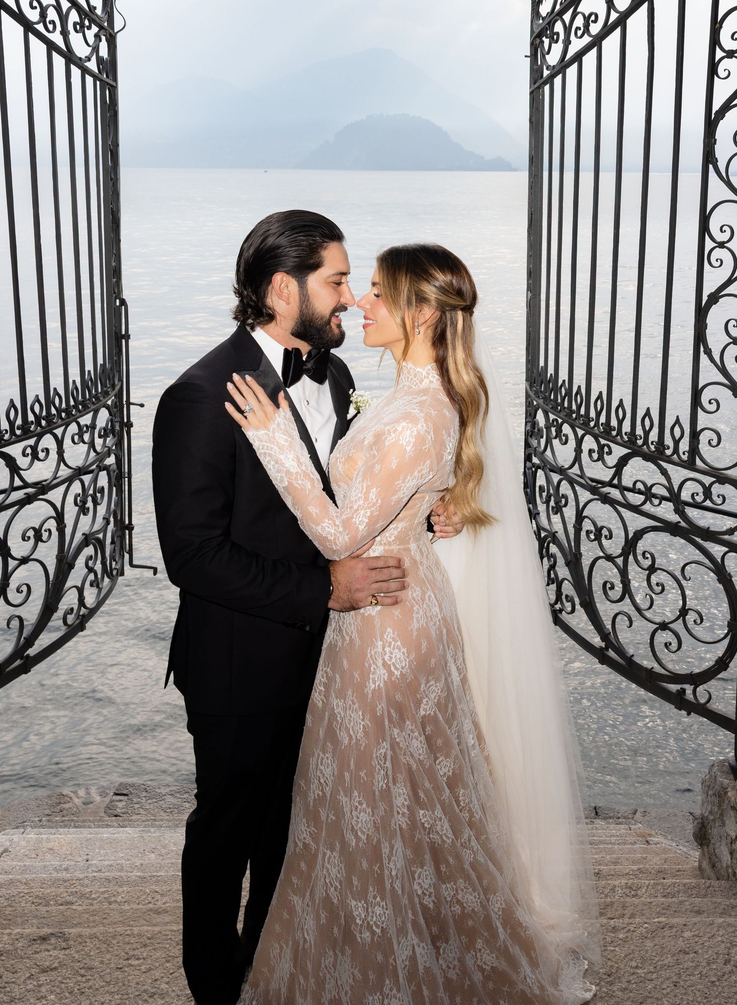 Intimate wedding portraits against an ornate iron gate with scenic coastal views.