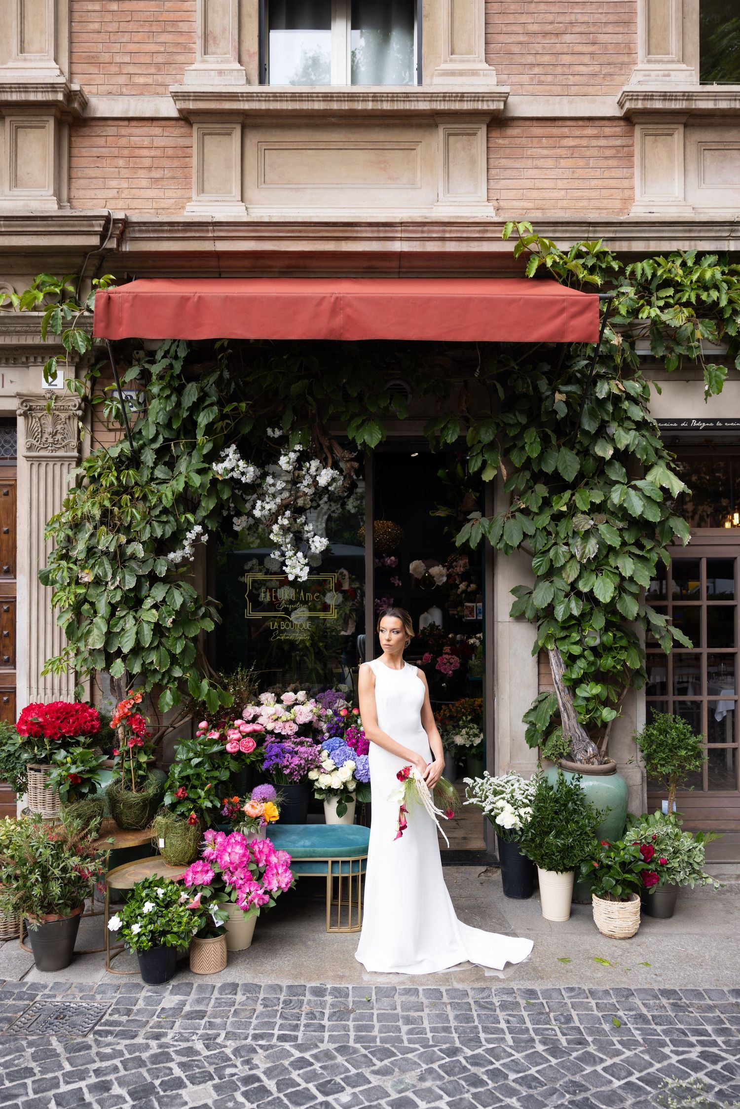A scenic storefront with climbing vines and cobblestone path creates perfect wedding photo backdrop.