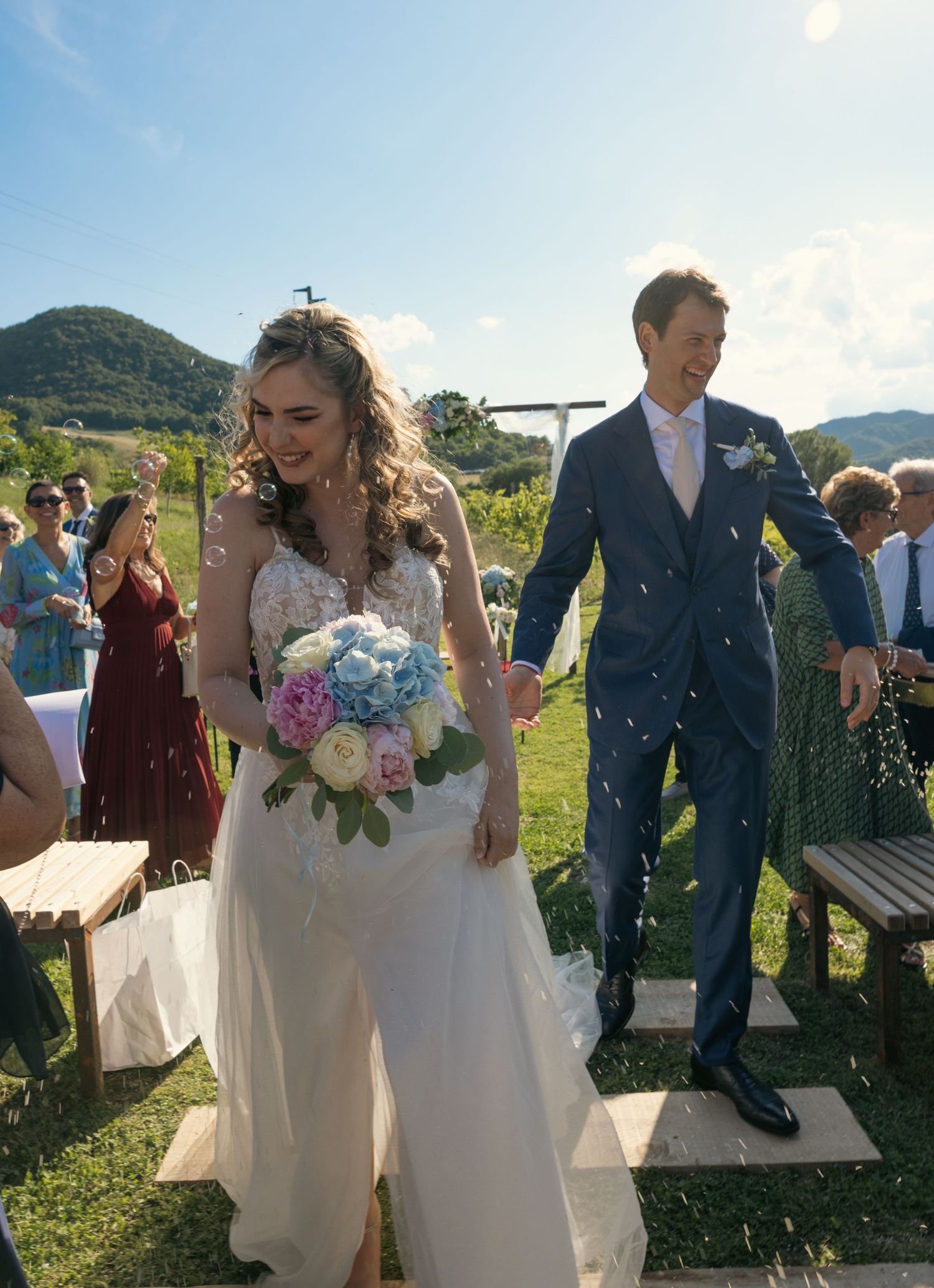 Wedding celebration sequence showing guests throwing confetti in a scenic mountain vineyard setting.
