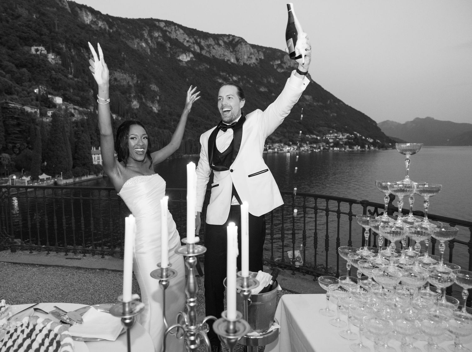 A black and white panoramic collage of wedding celebration moments at a scenic lakeside venue with mountains in background.