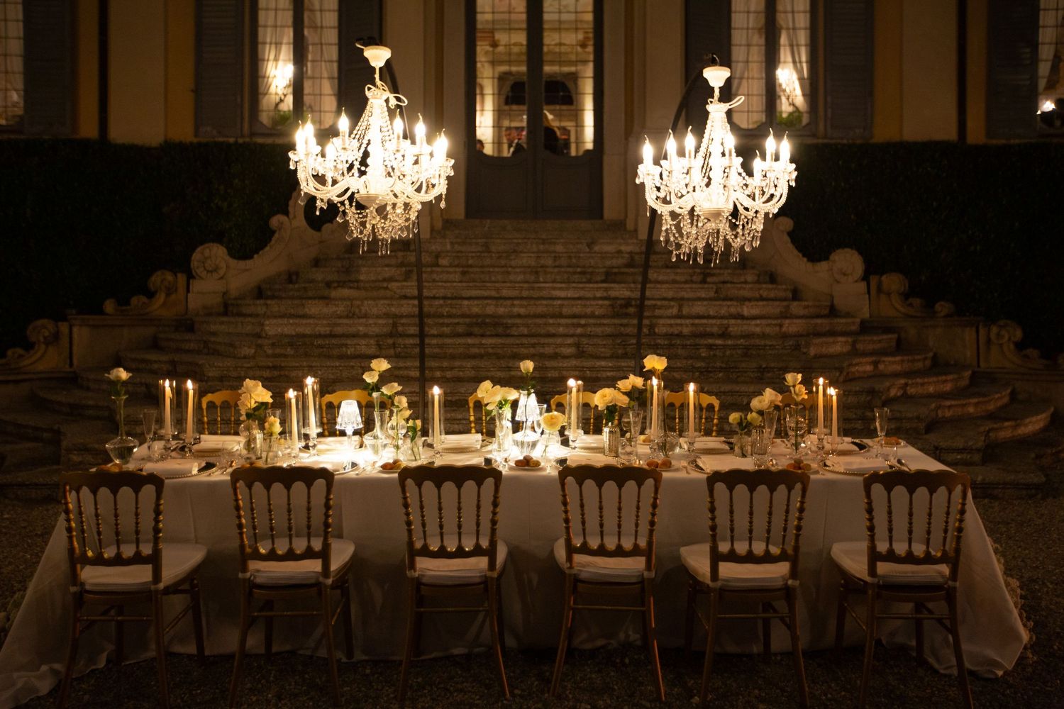 Indoor wedding reception with multiple crystal chandeliers and elegant table settings.