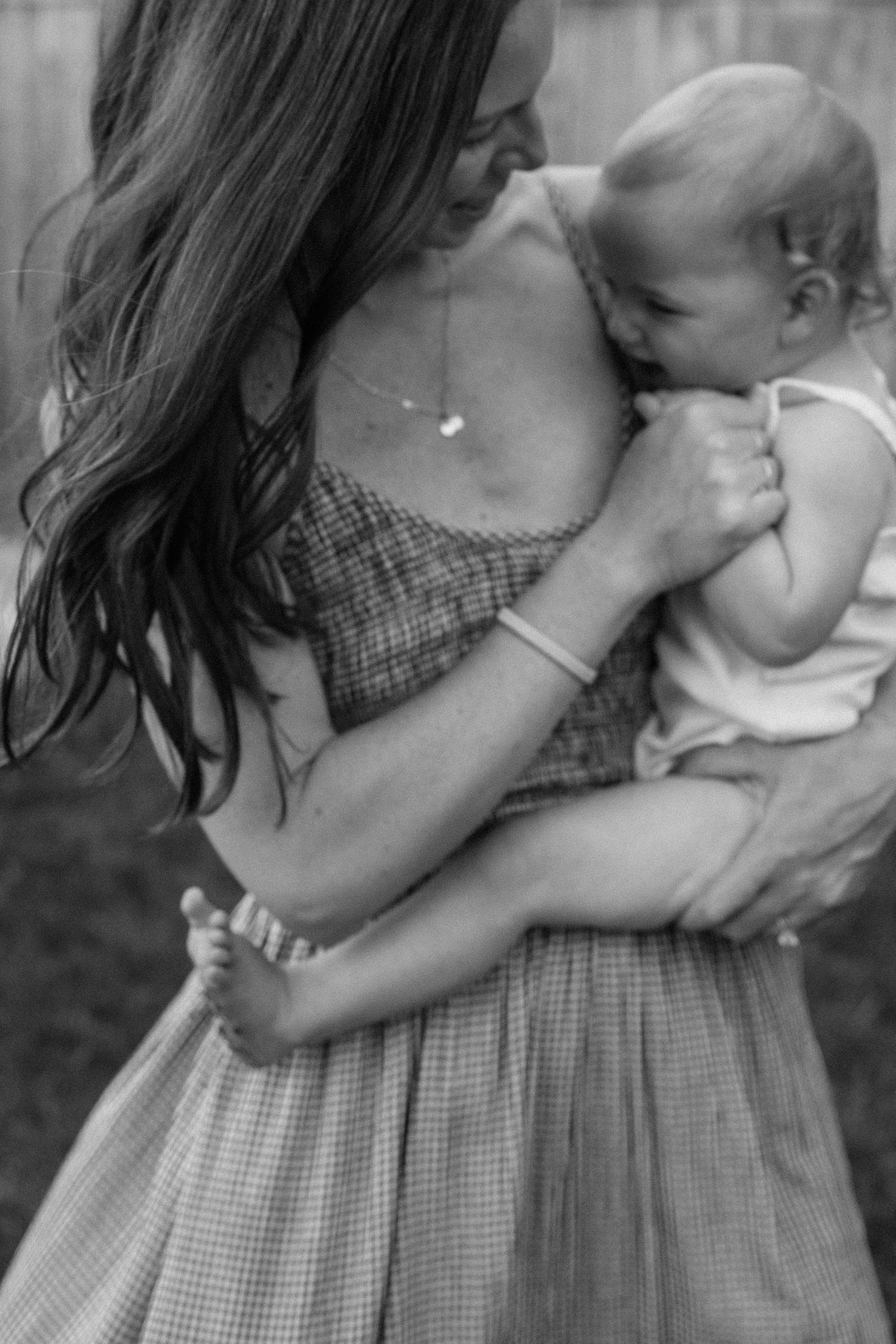 Candid black and white close-up of tender family moments outdoors.