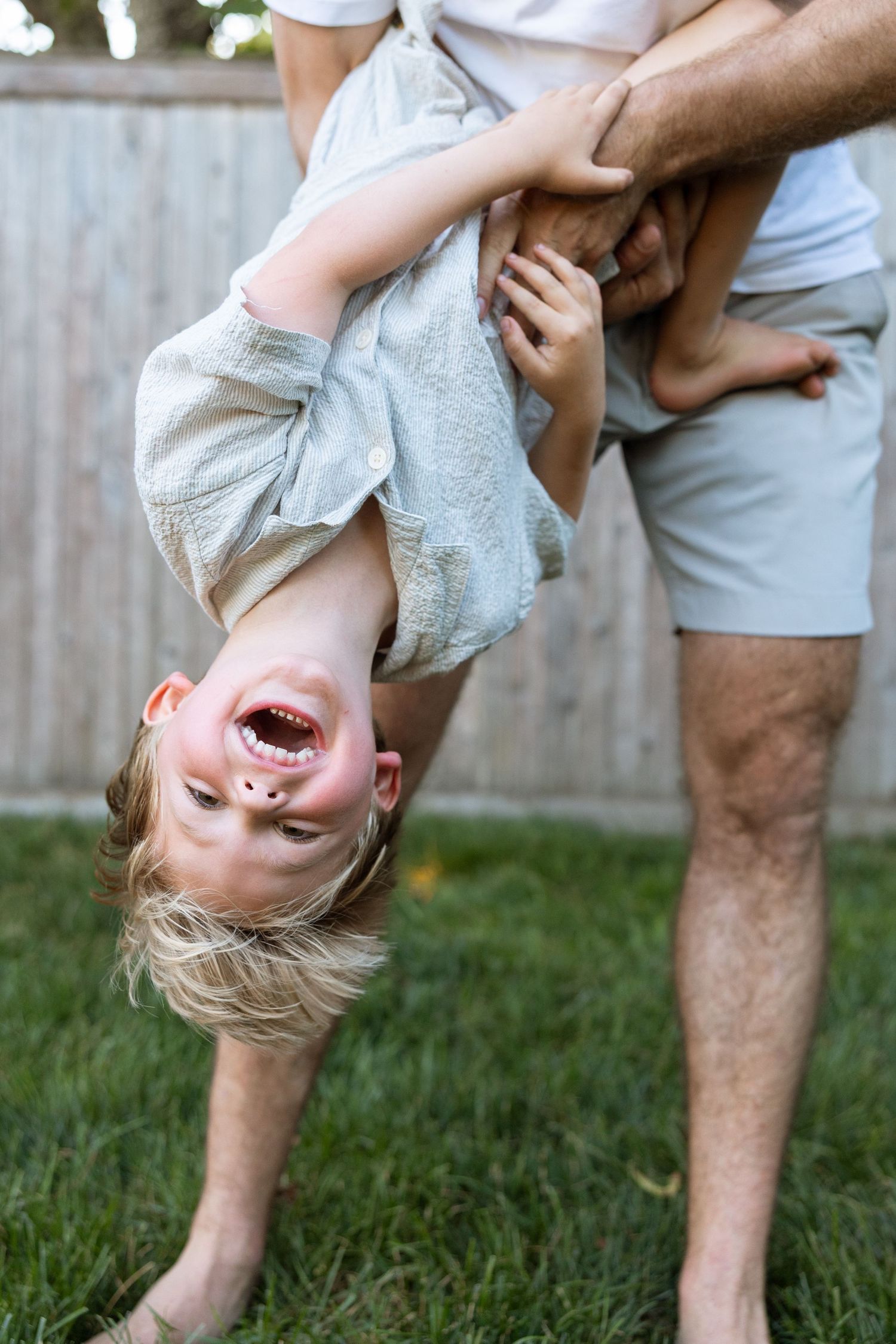 Playful upside-down moments shared between family members in a backyard setting.