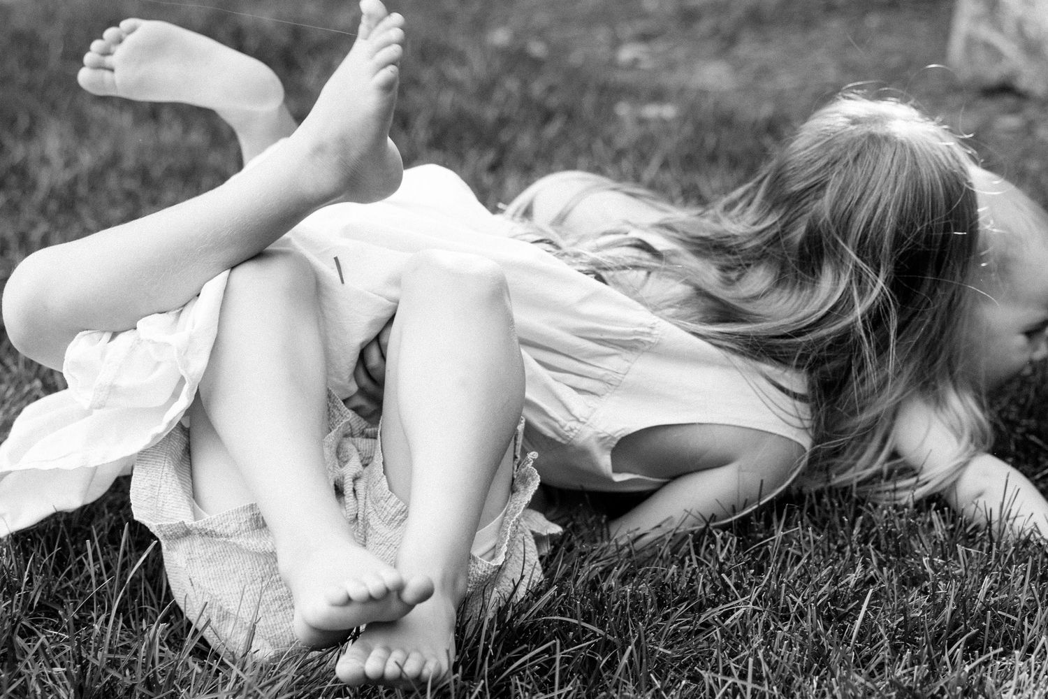 Intimate black and white photograph capturing playful moments in the grass.