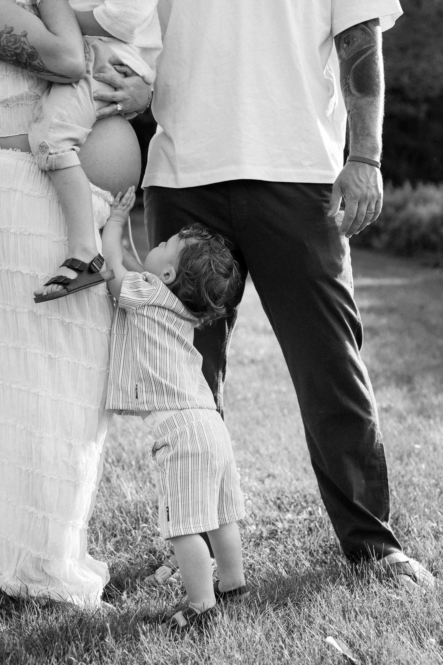Close-up detail of legs and white dresses as people gather outdoors for a romantic photo shoot or celebration.