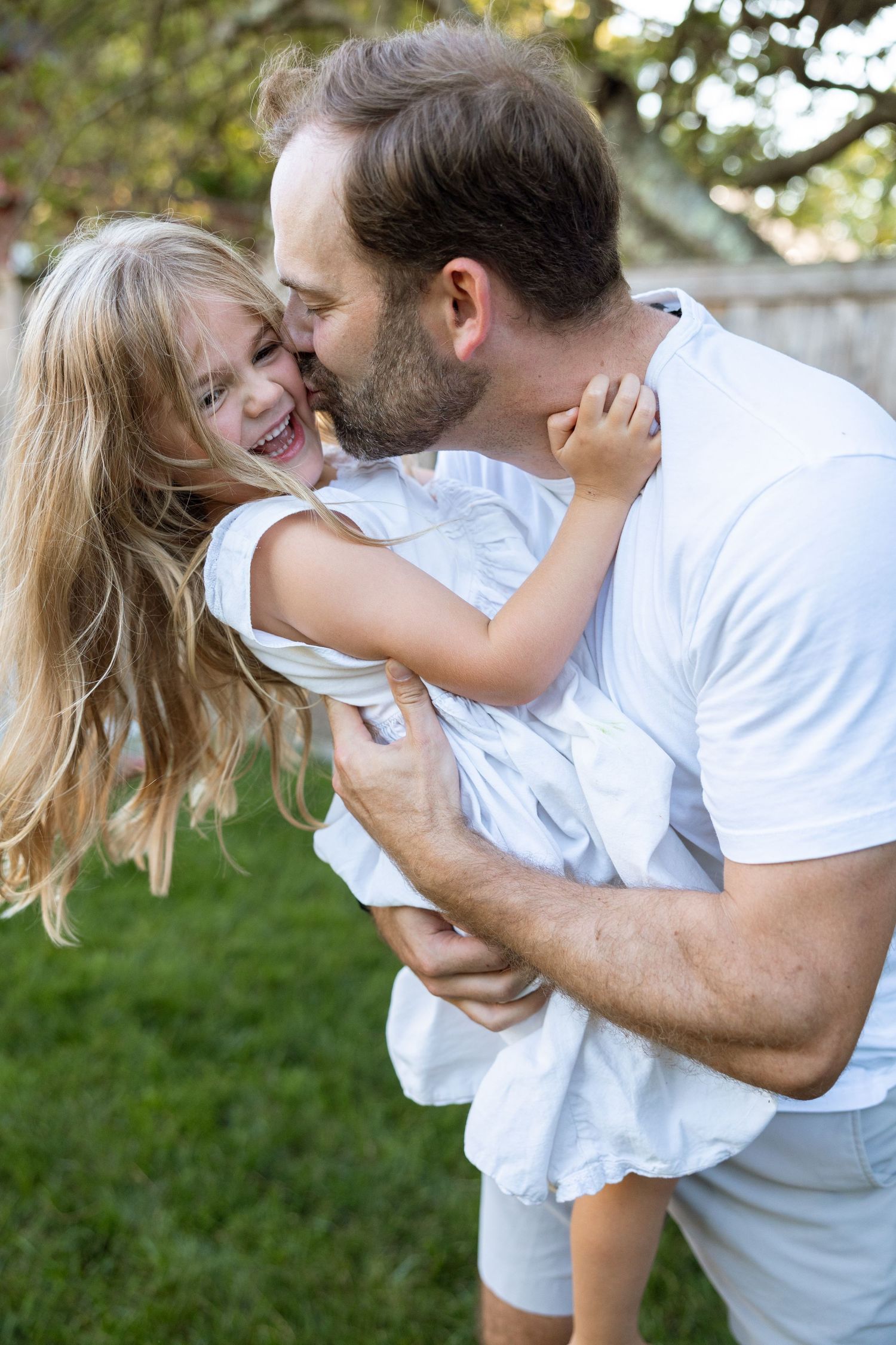 Joyful family interaction captured in warm sunlight on a grassy lawn.