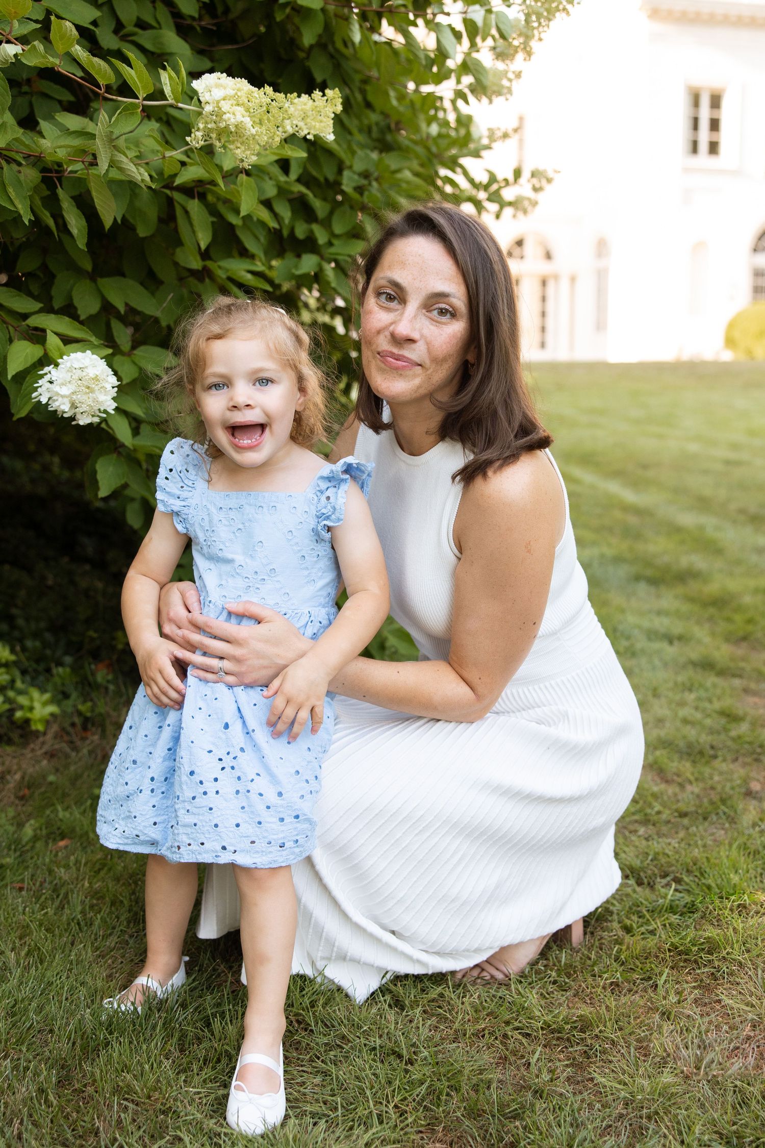 A heartwarming outdoor photoshoot showing tender moments between two people in white and blue dresses on green grass.