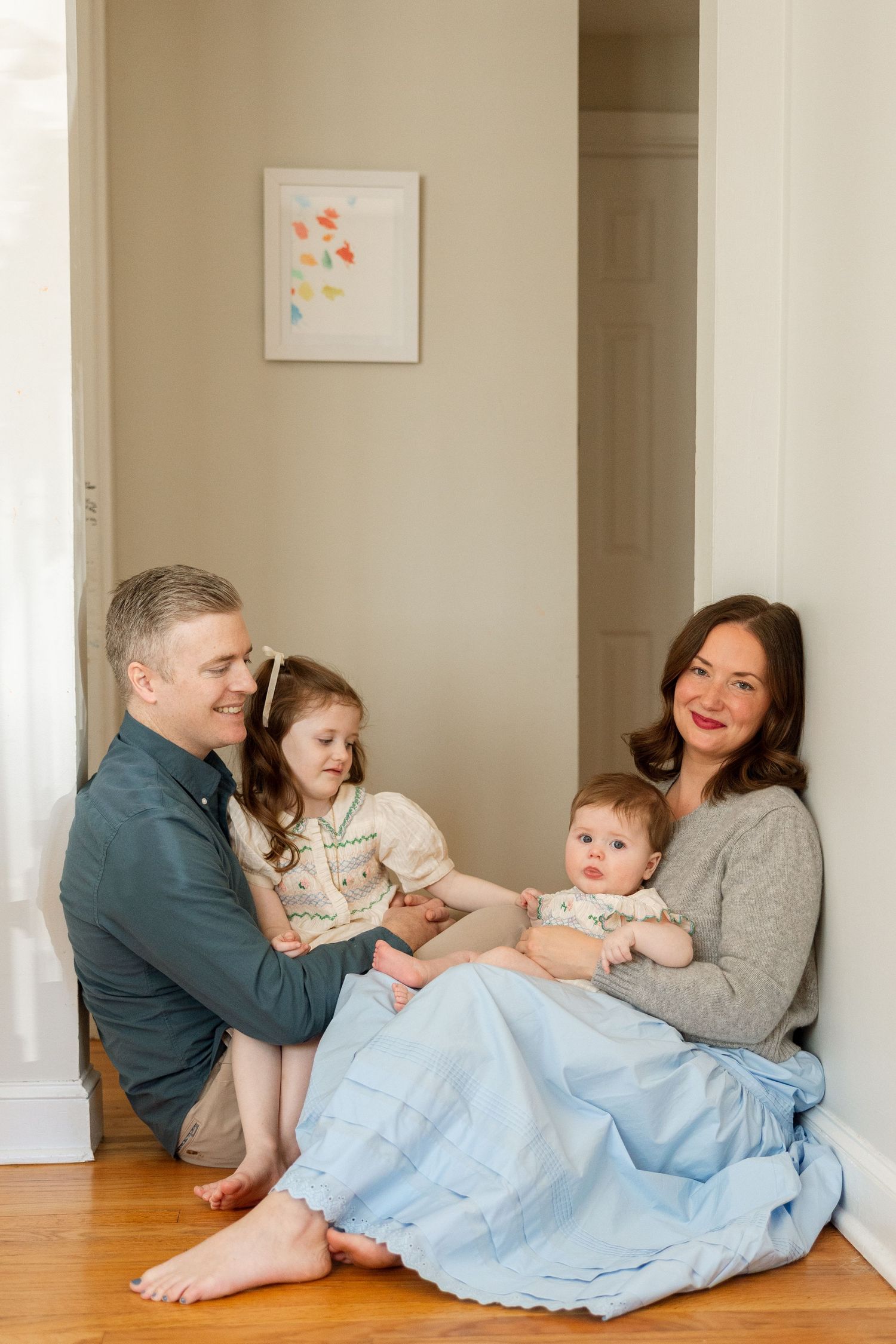 Family lies together on hardwood floor, sharing playful and candid moments in series of connected images.