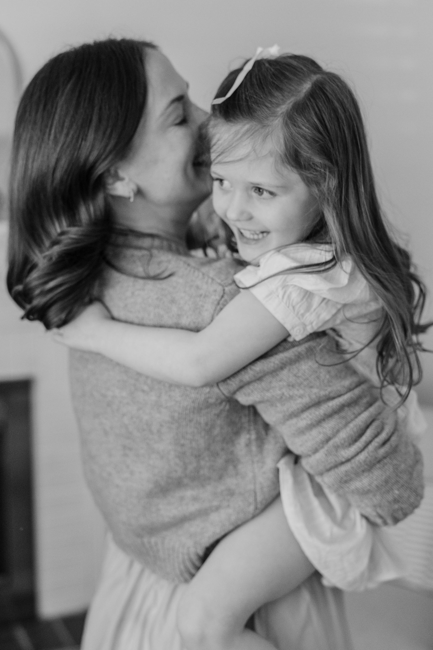 A tender black and white portrait of parent and child sharing a loving embrace and playful moment together.