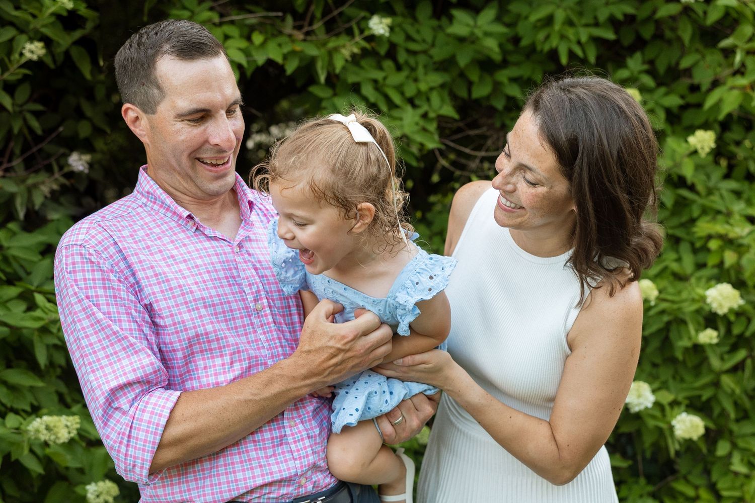 A happy family shares a joyful moment together outdoors against a backdrop of green foliage.