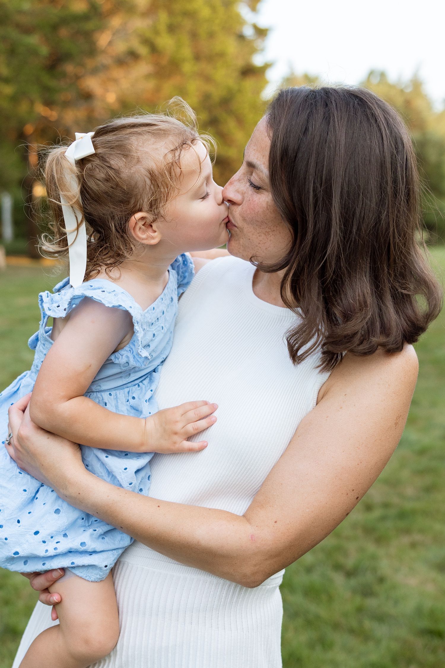 A tender moment shared between parent and child in an outdoor garden setting at sunset.