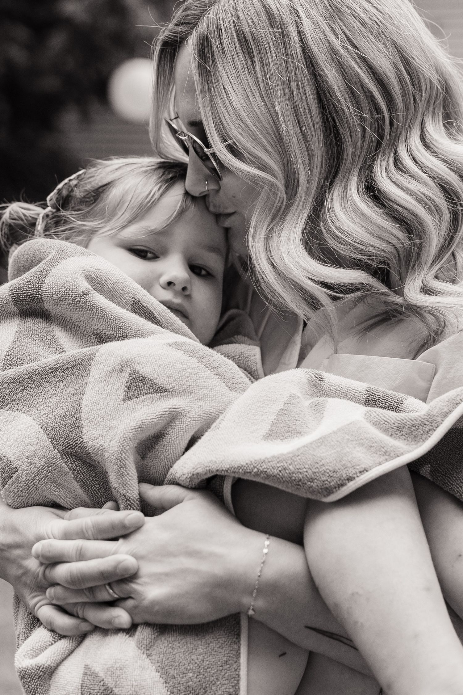 Mother and child share tender moments of affection and comfort wrapped in a cozy gray blanket.