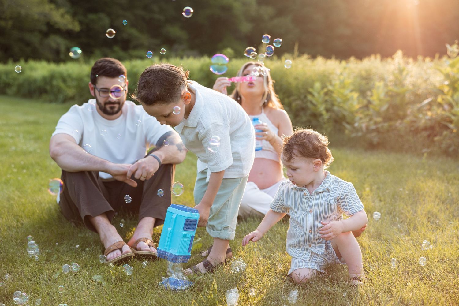 Family blowing bubbles together in a golden sunlit meadow during a summer evening.