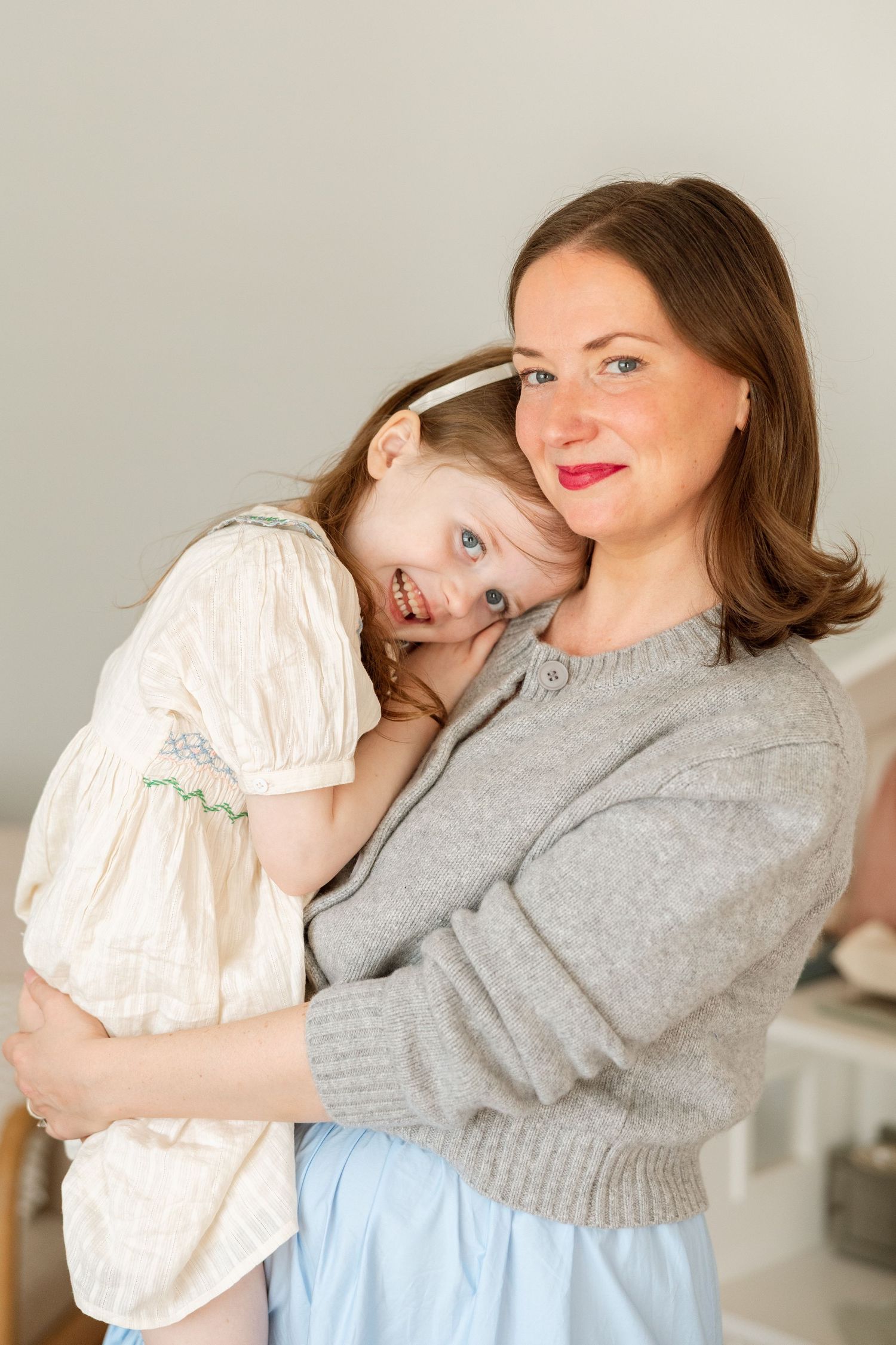 A pair embraces warmly in a series of tender moments, wearing a grey sweater and white blouse against a neutral background.